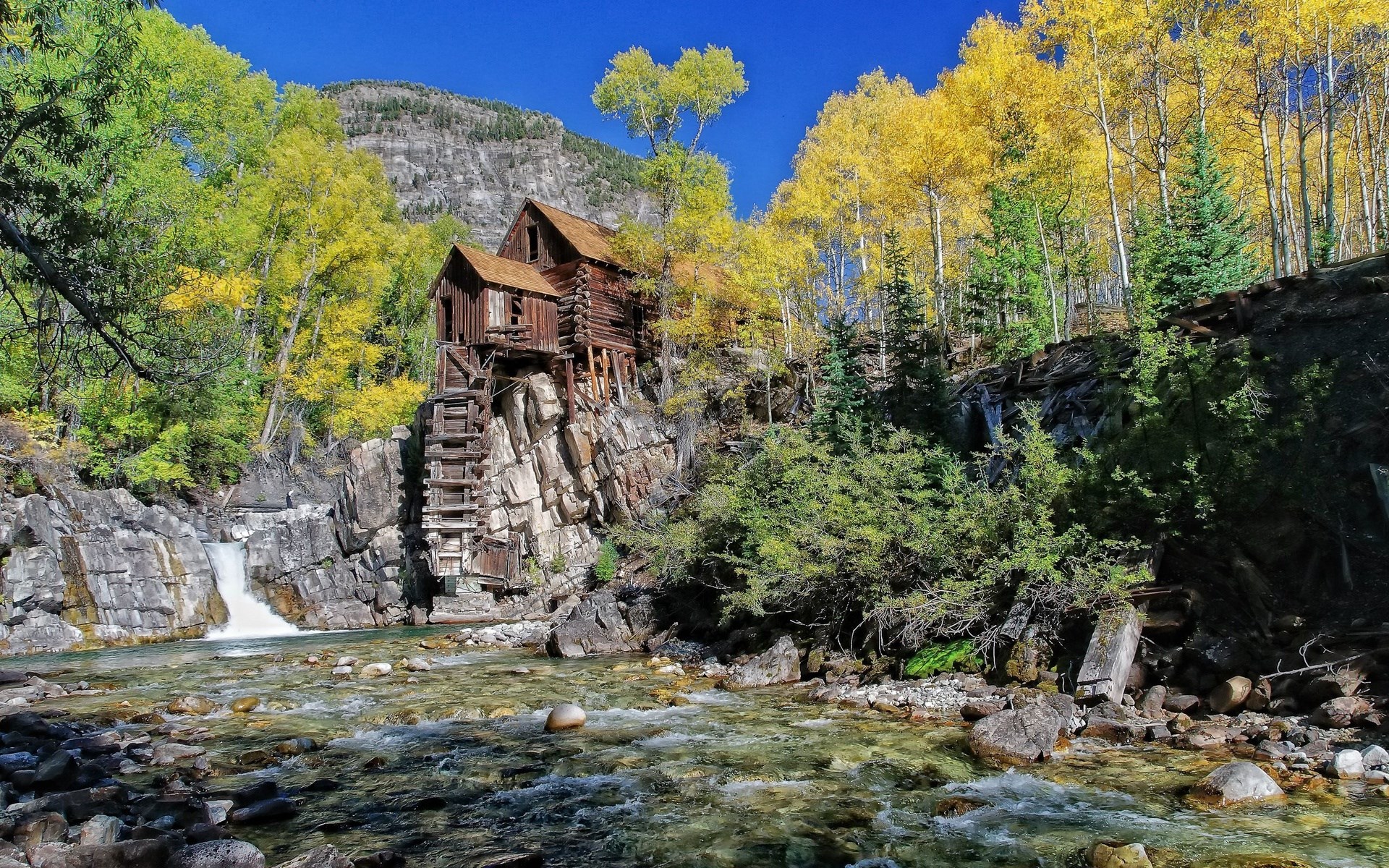 Old wooden mill on a rocky cliff by a river HD Wallpaper