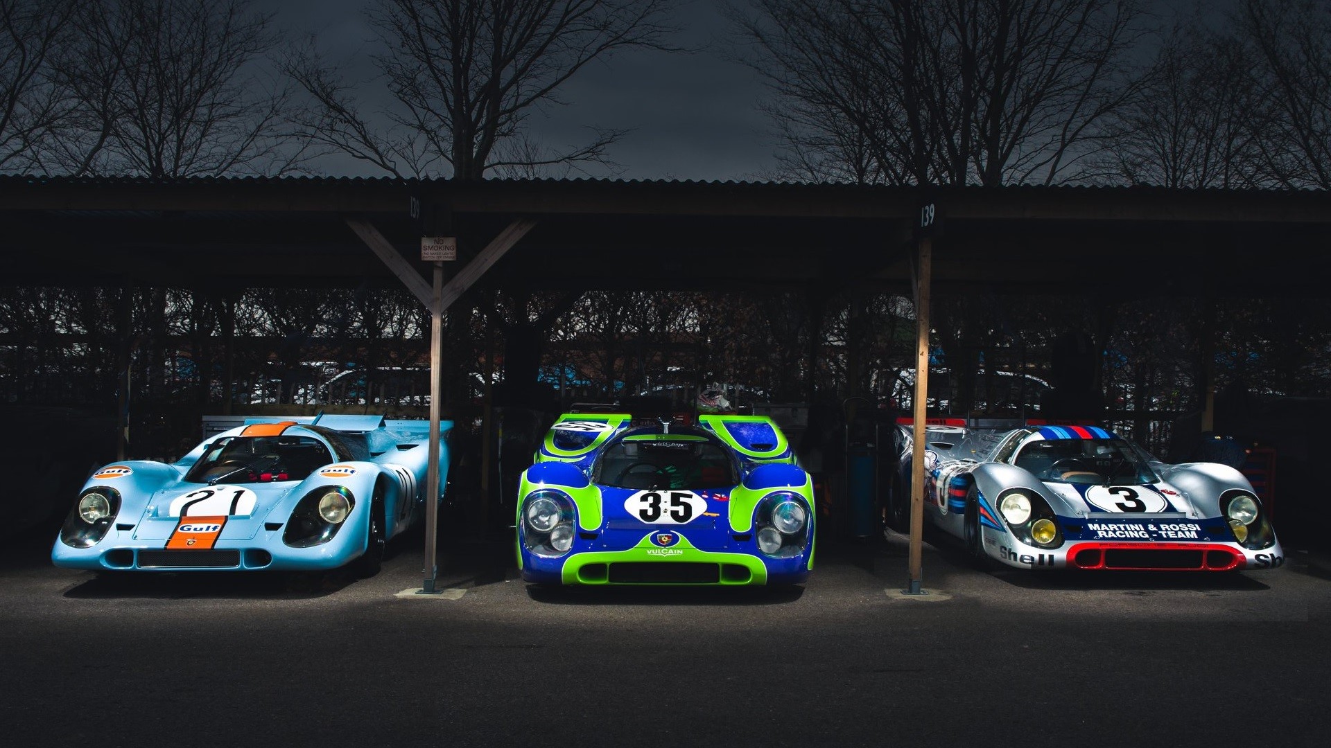 Three vintage Porsche race cars under a canopy HD Wallpaper