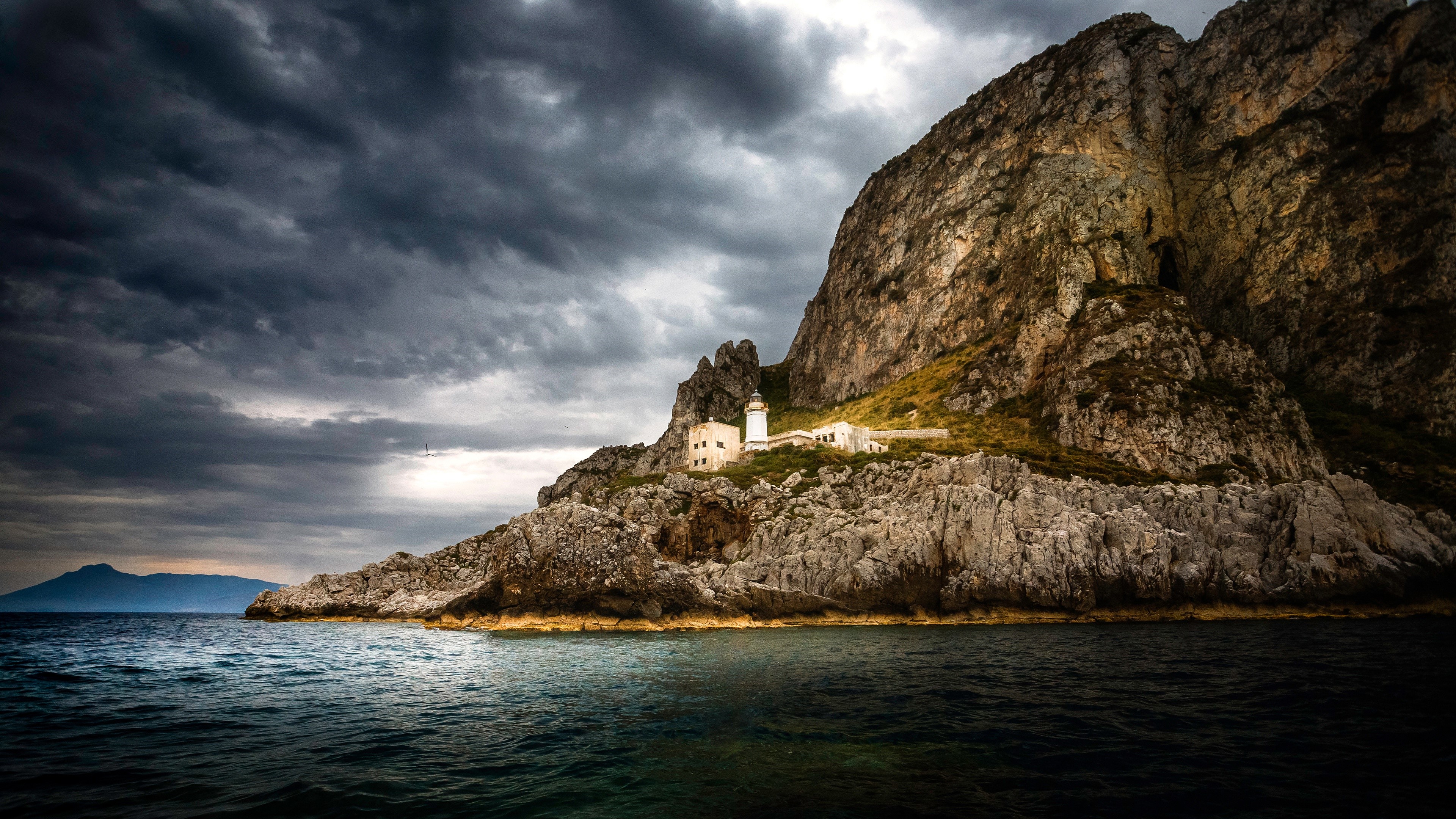 Lighthouse on a rocky cliff by the sea HD Wallpaper