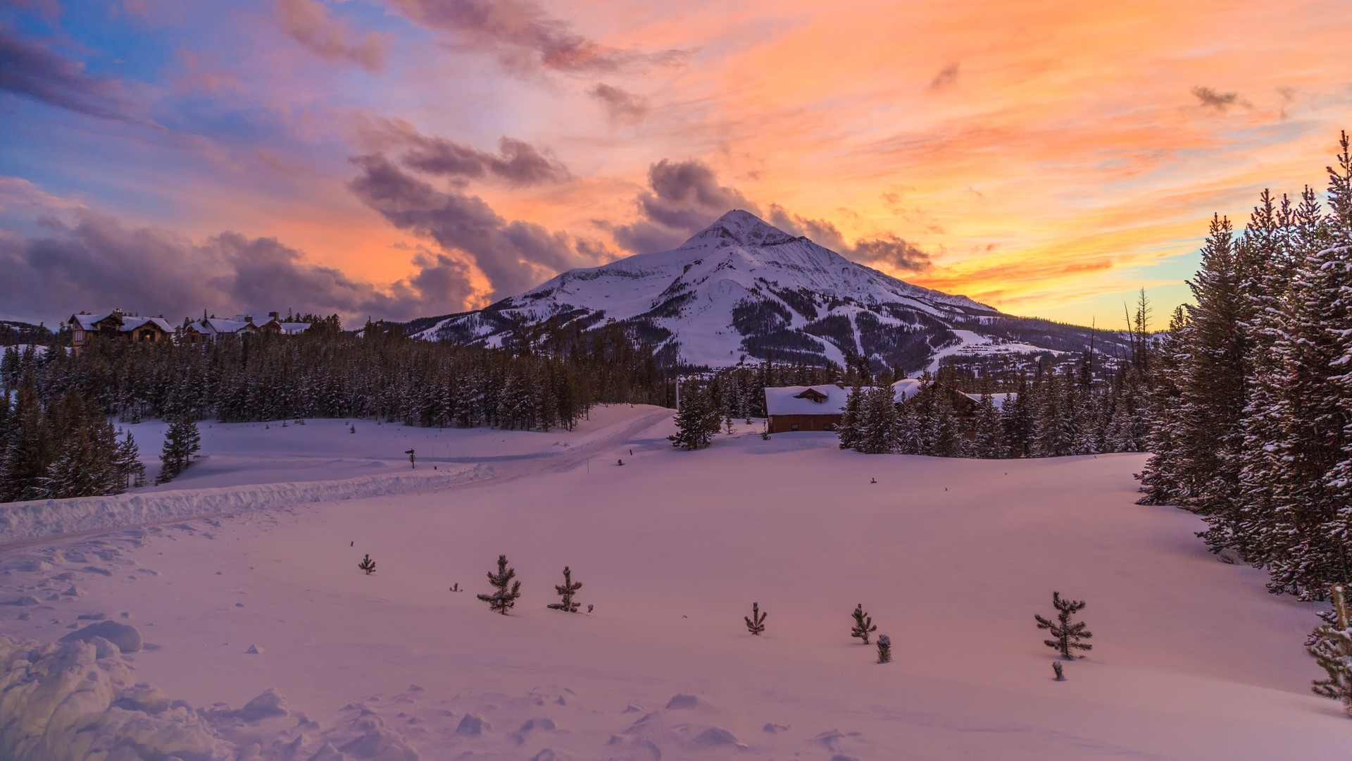 Snowy mountain landscape at sunset with trees and houses HD Wallpaper
