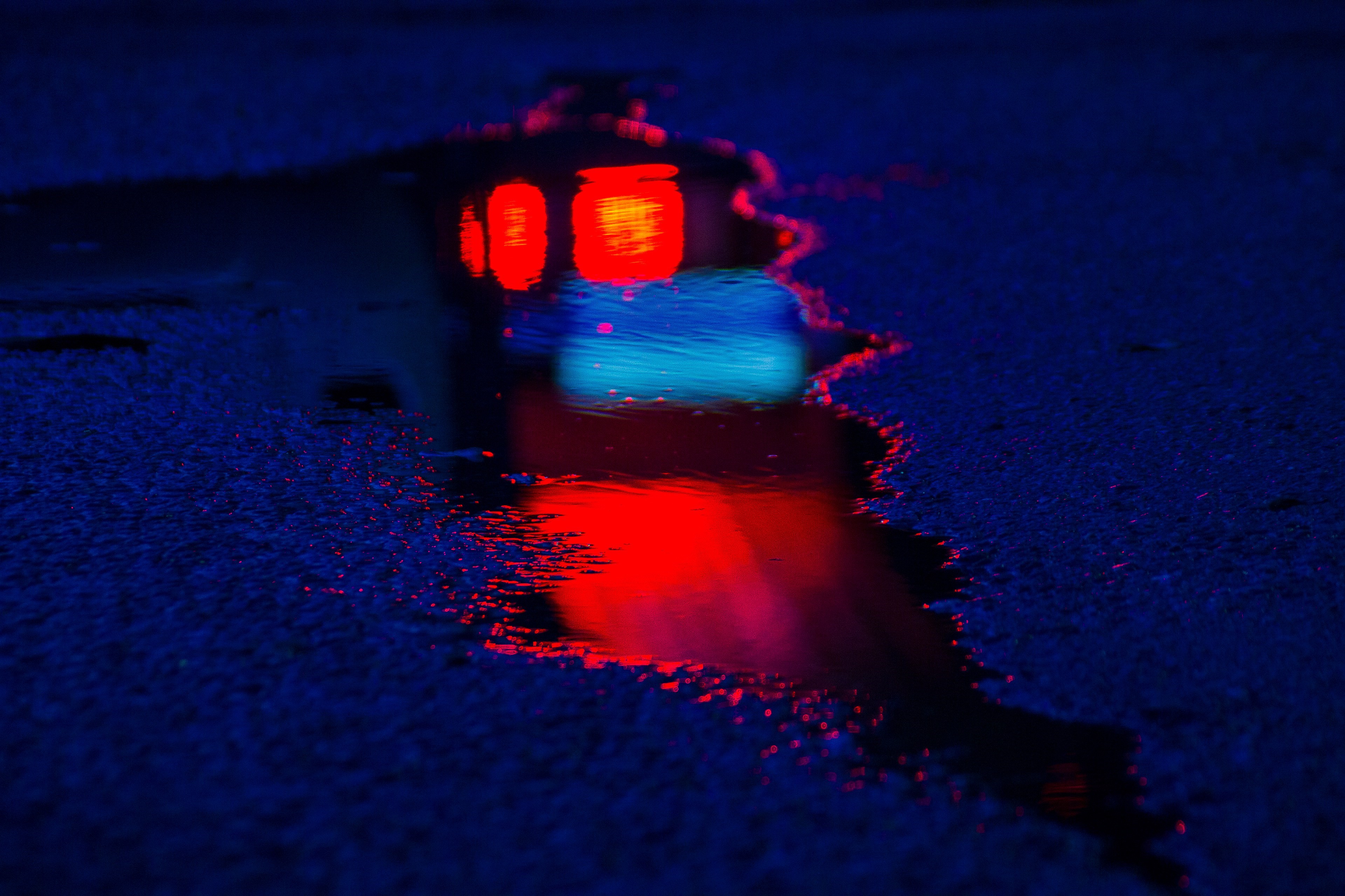 Reflection of red and blue lights in a puddle on asphalt HD Wallpaper