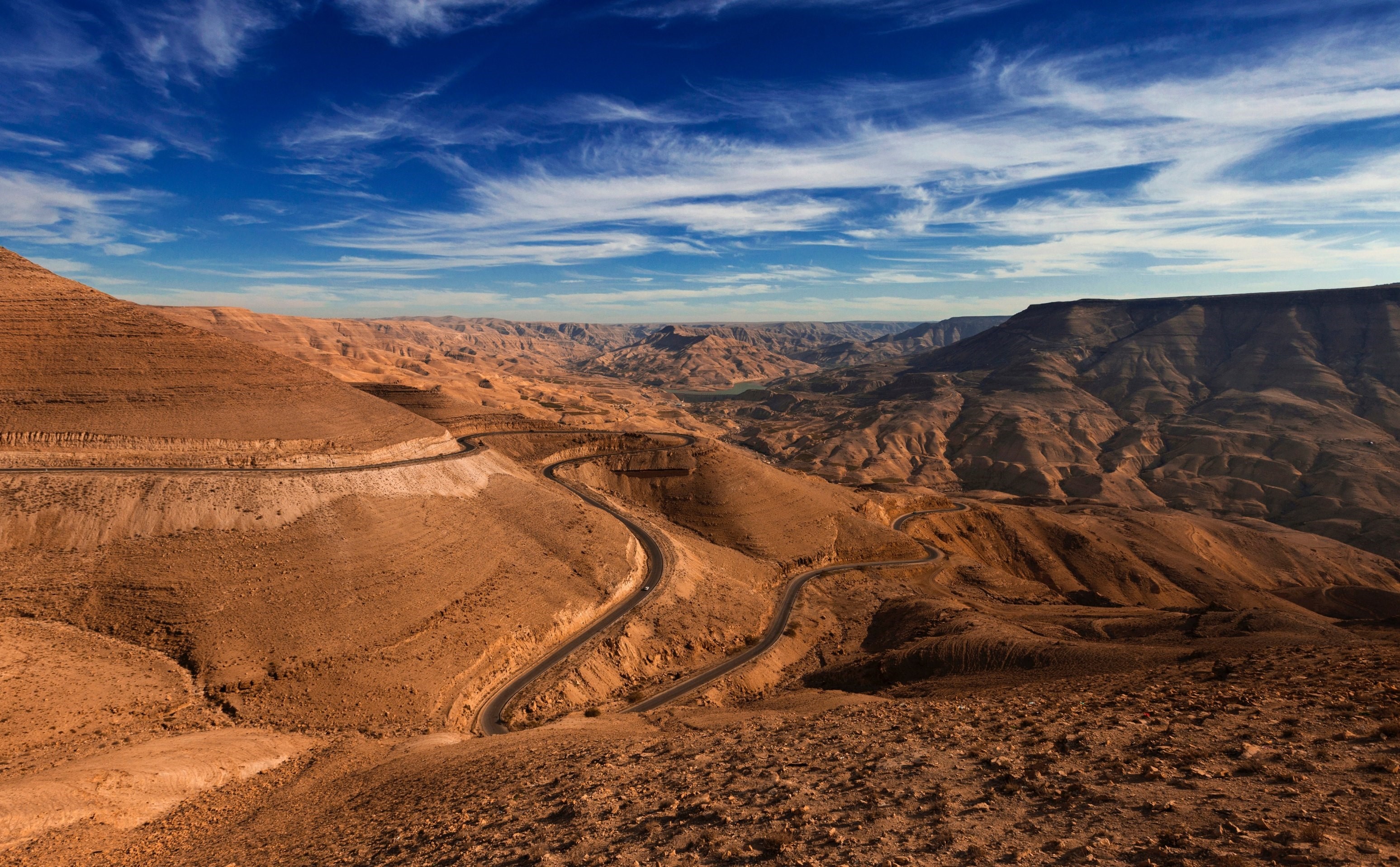 Winding road through a desert canyon under a blue sky HD Wallpaper