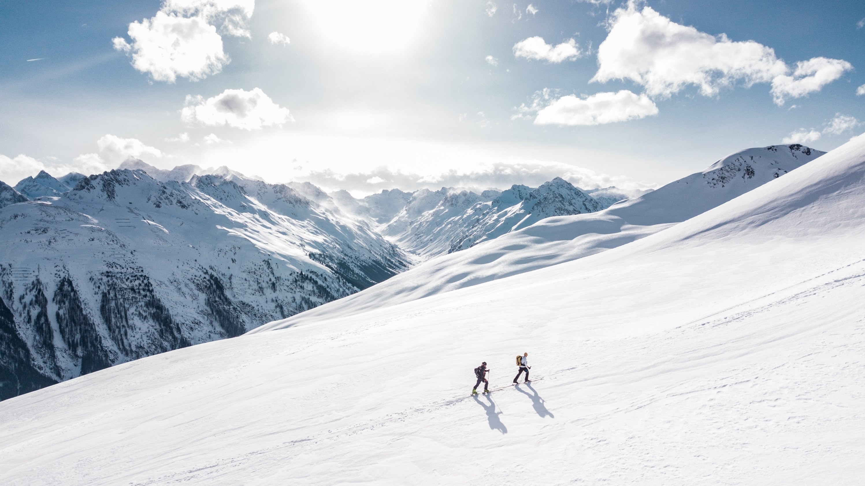 Two hikers ascend a snowy mountain slope HD Wallpaper