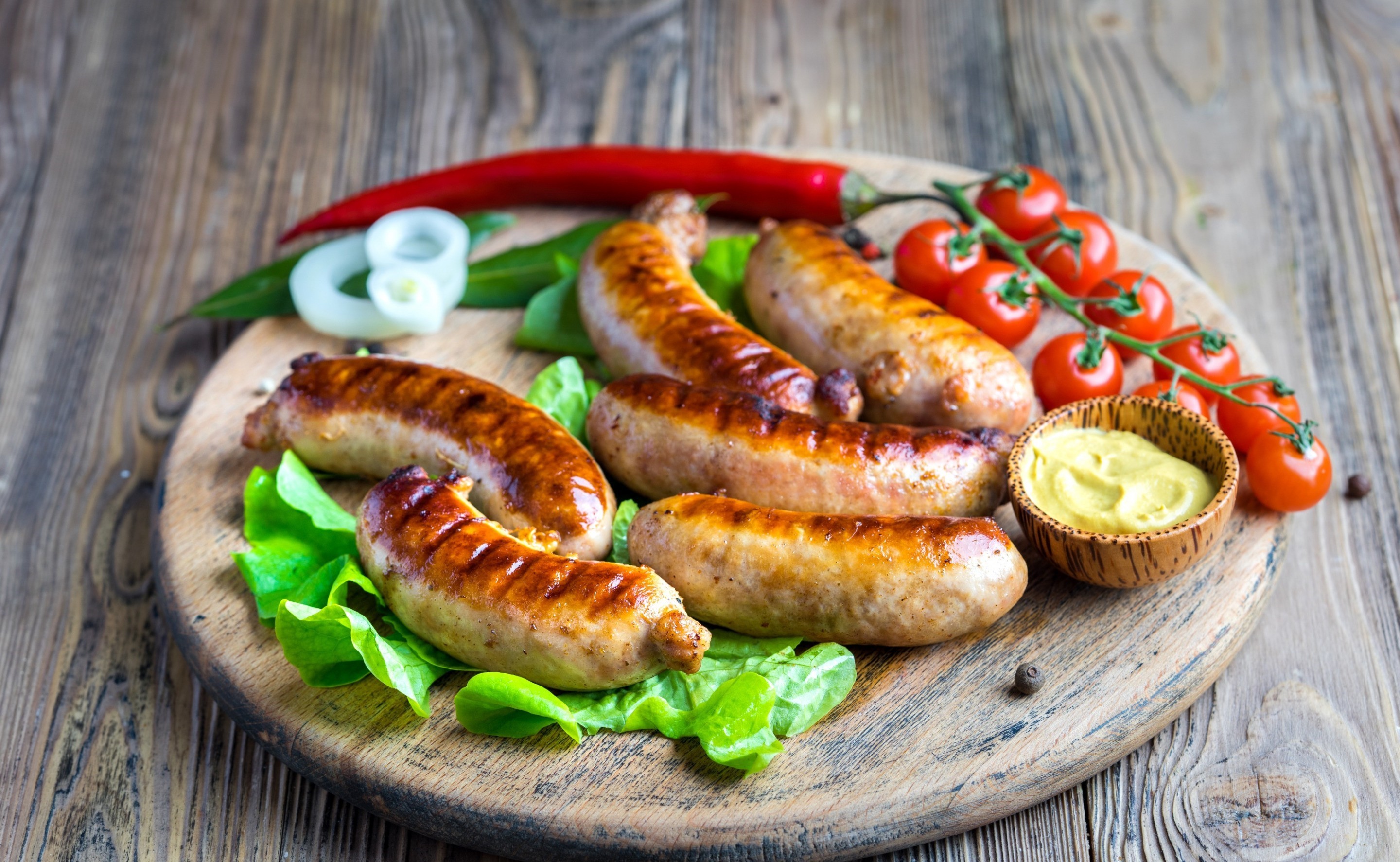 Grilled sausages with tomatoes and mustard on a wooden board HD Wallpaper