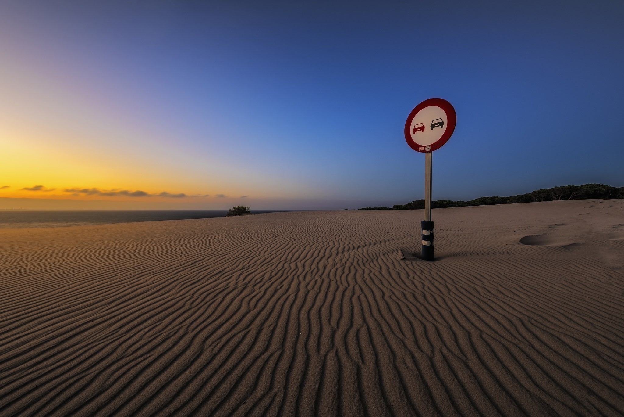 No overtaking sign in a sand dune landscape at sunset HD Wallpaper