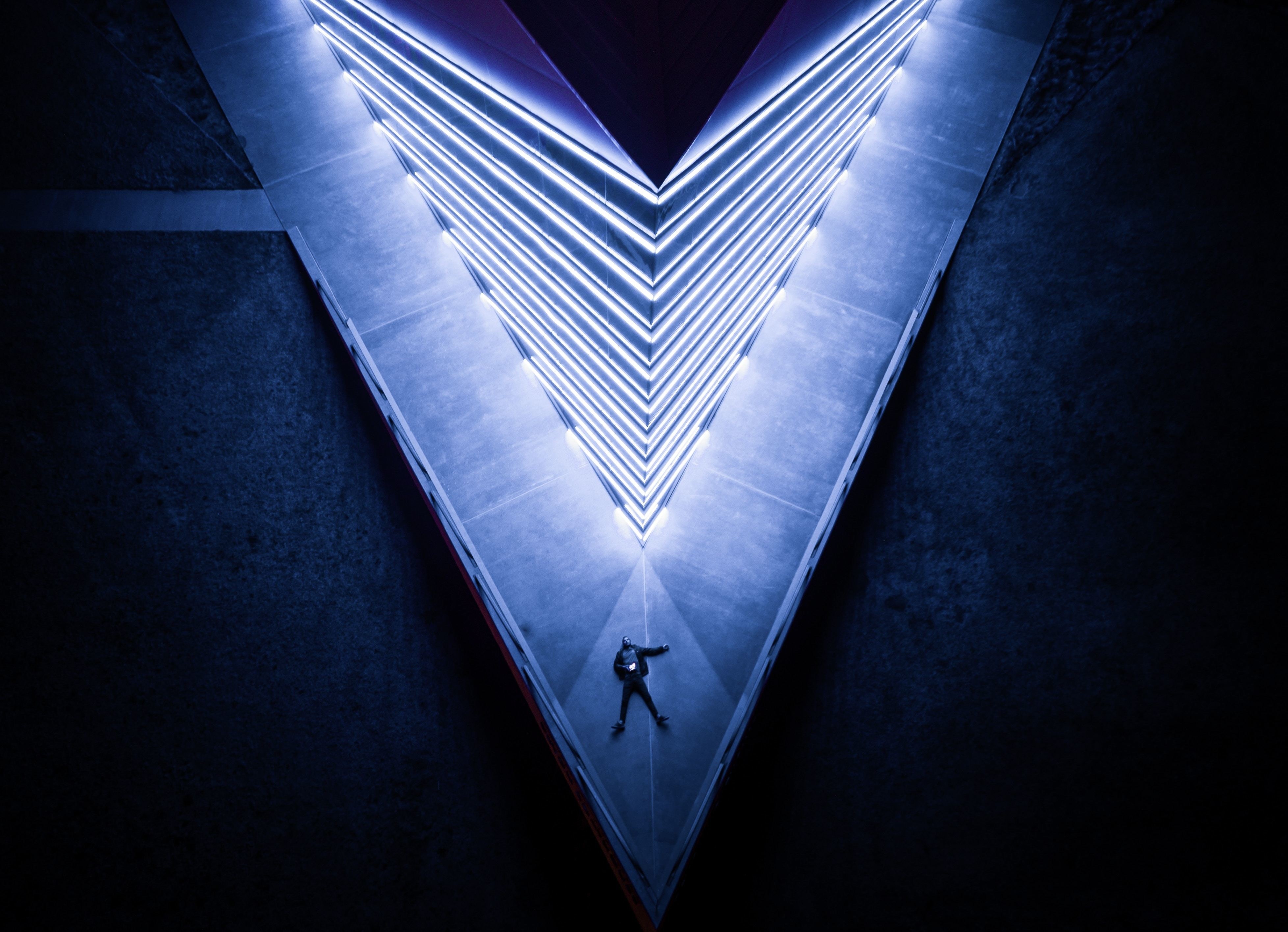 Man standing in a V-shaped building with neon lights HD Wallpaper