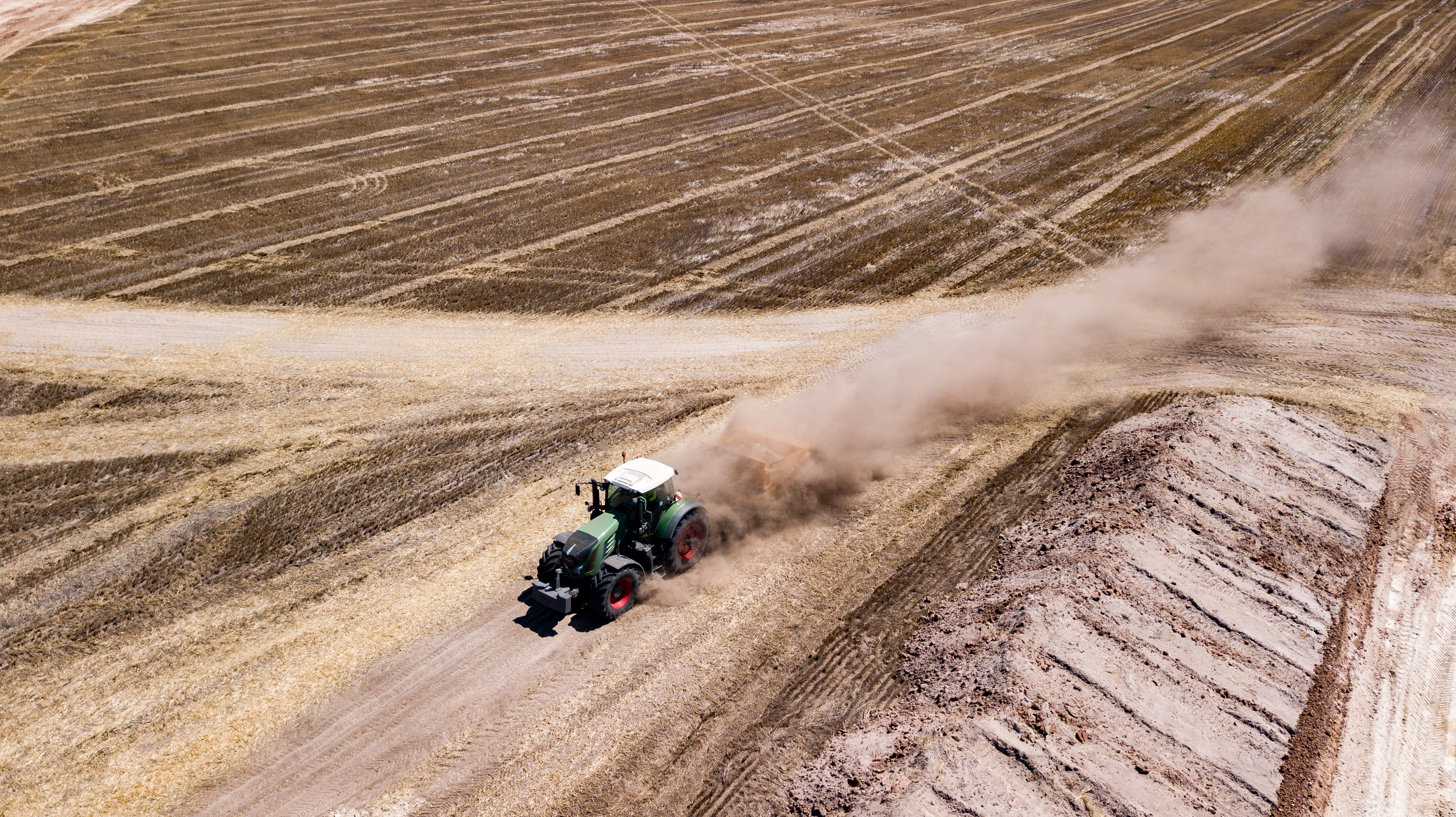 Tractor plowing a dusty field HD Wallpaper