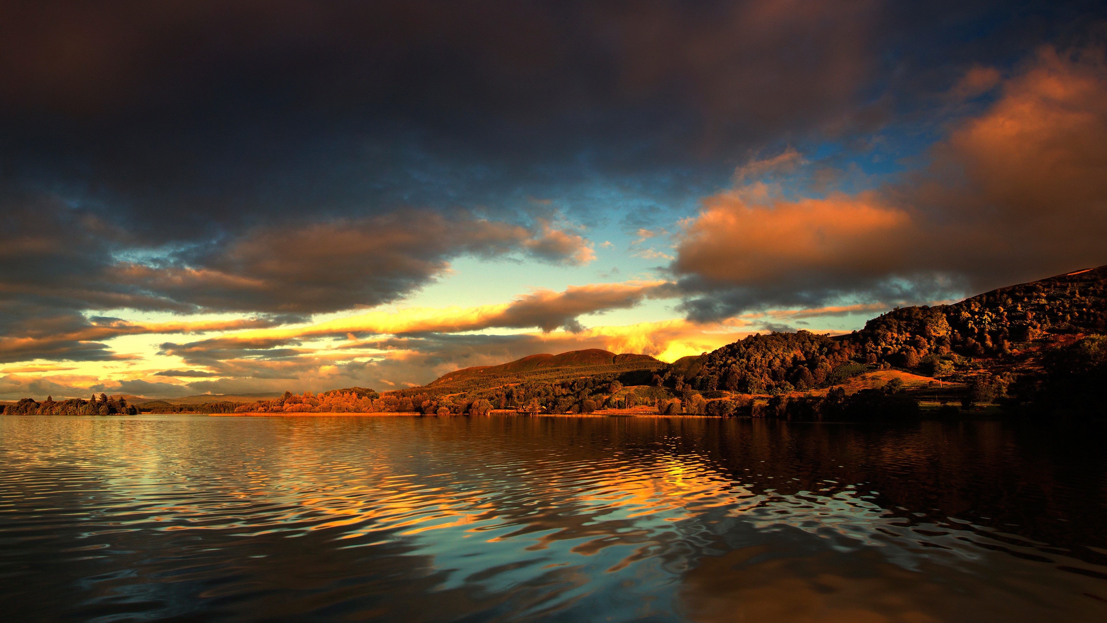 Sunset over a lake with dark clouds HD Wallpaper
