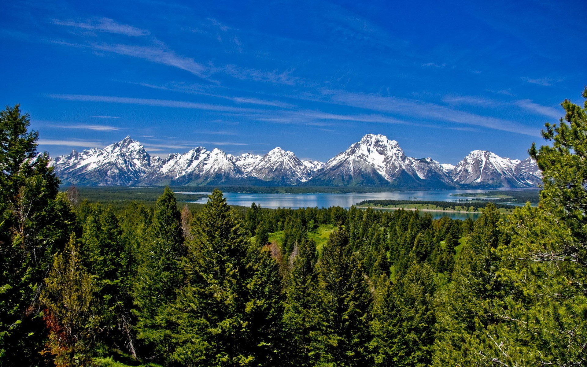 Snow-capped mountains over a forest and lake HD Wallpaper