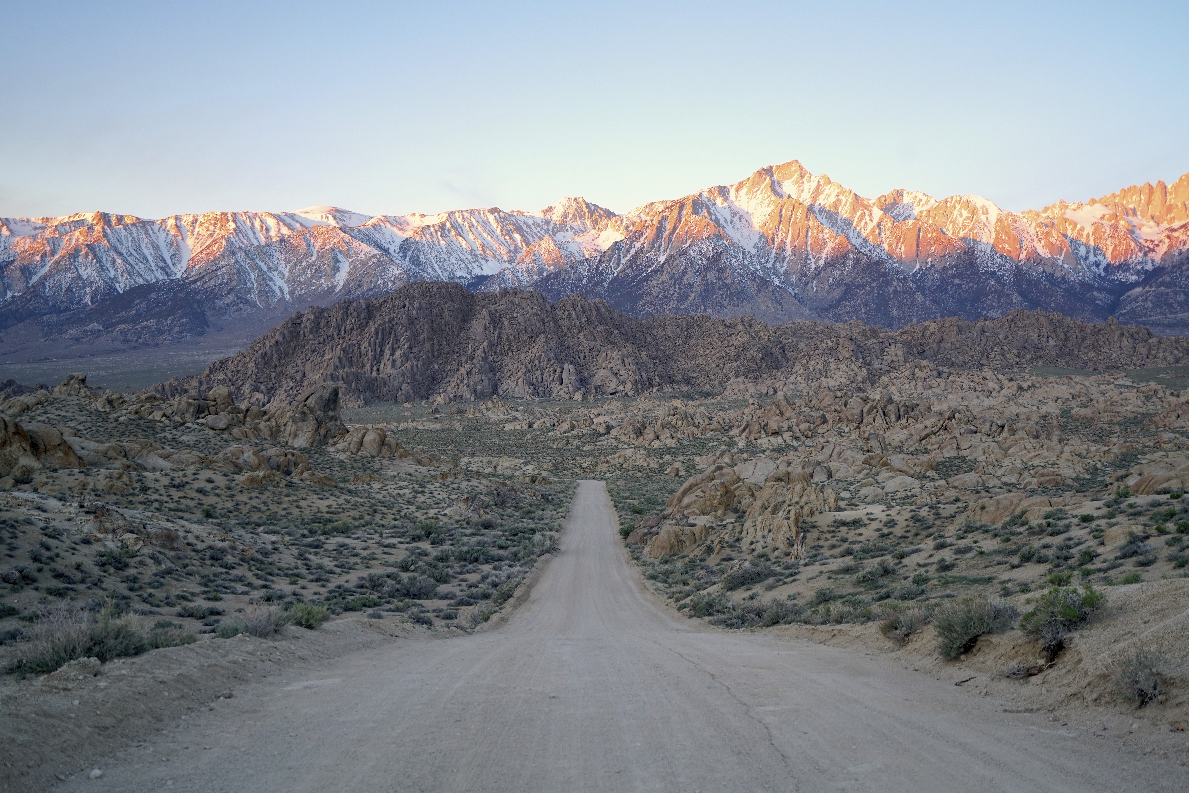 Dirt road leading to snow-capped Sierra Nevada mountains HD Wallpaper