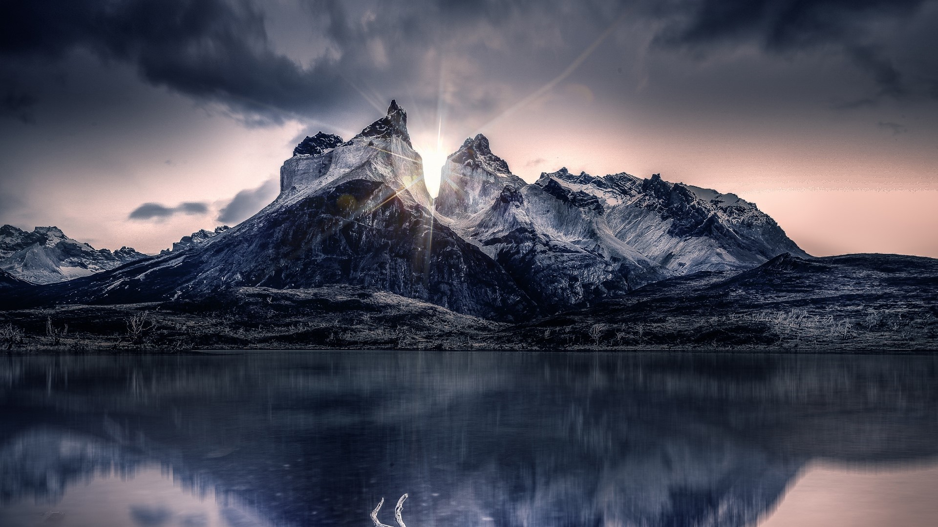 Sunlight breaking through mountains reflected in a lake HD Wallpaper