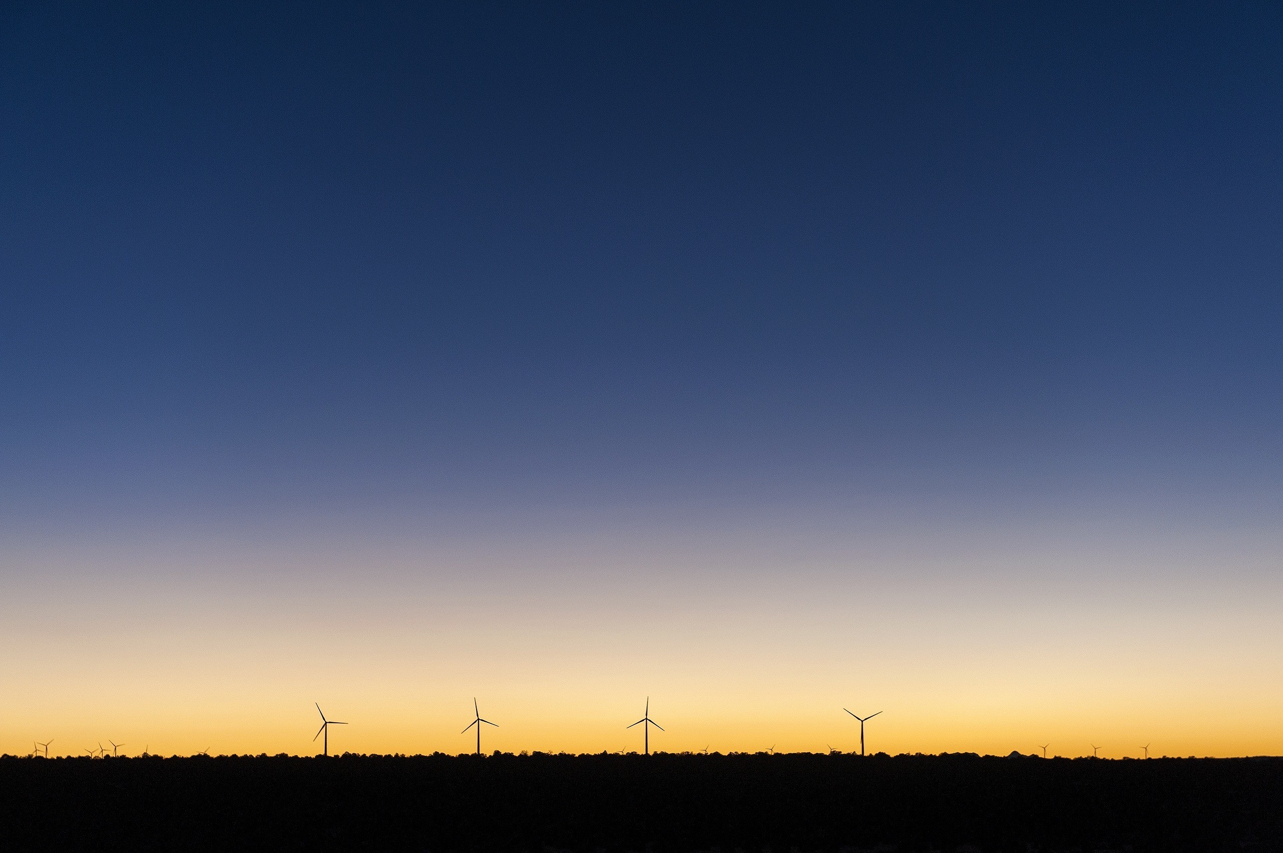 Wind farm silhouette against a sunset sky HD Wallpaper