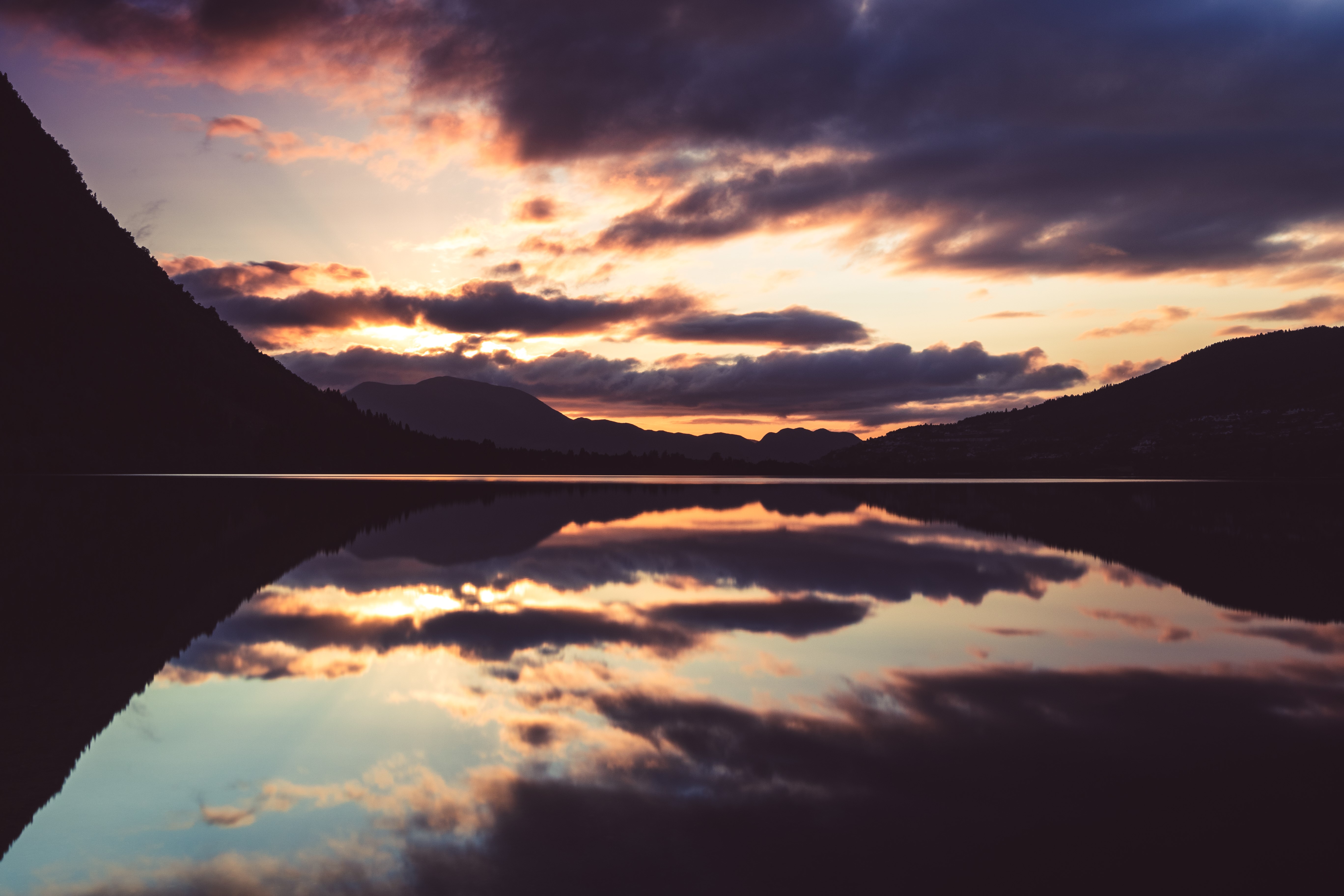Sunset over a calm lake with mountain silhouettes HD Wallpaper