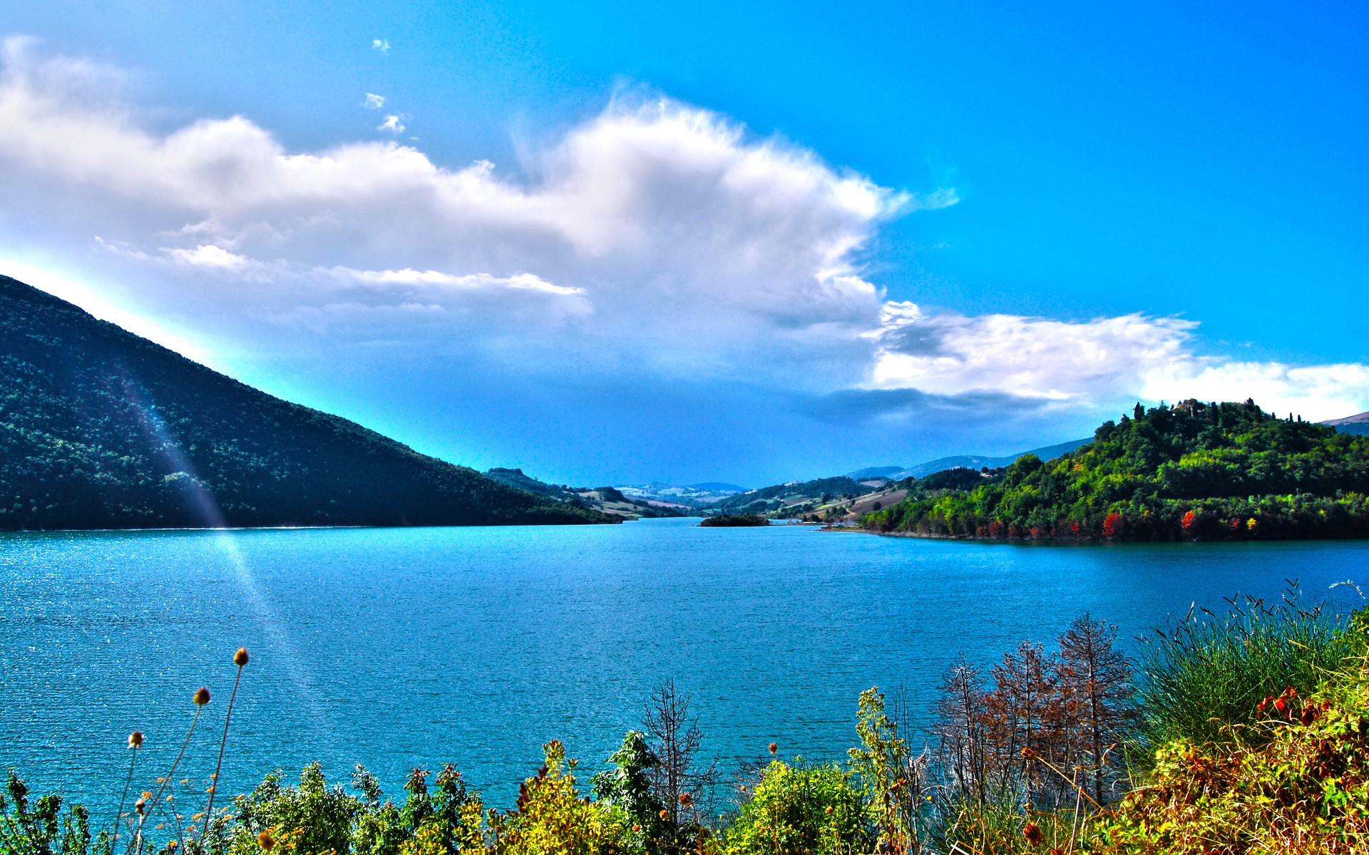 Lake surrounded by green hills under a blue sky HD Wallpaper