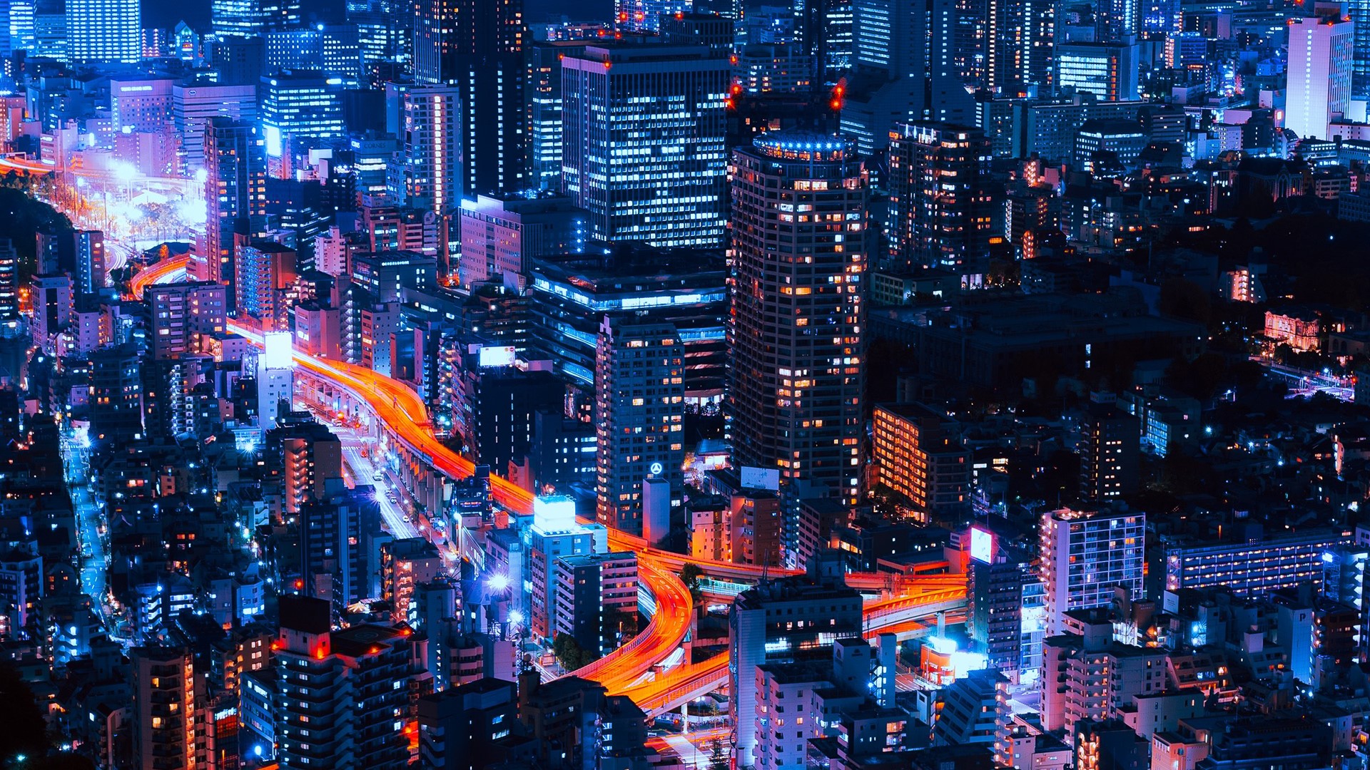 Nighttime cityscape with illuminated buildings and highways HD Wallpaper