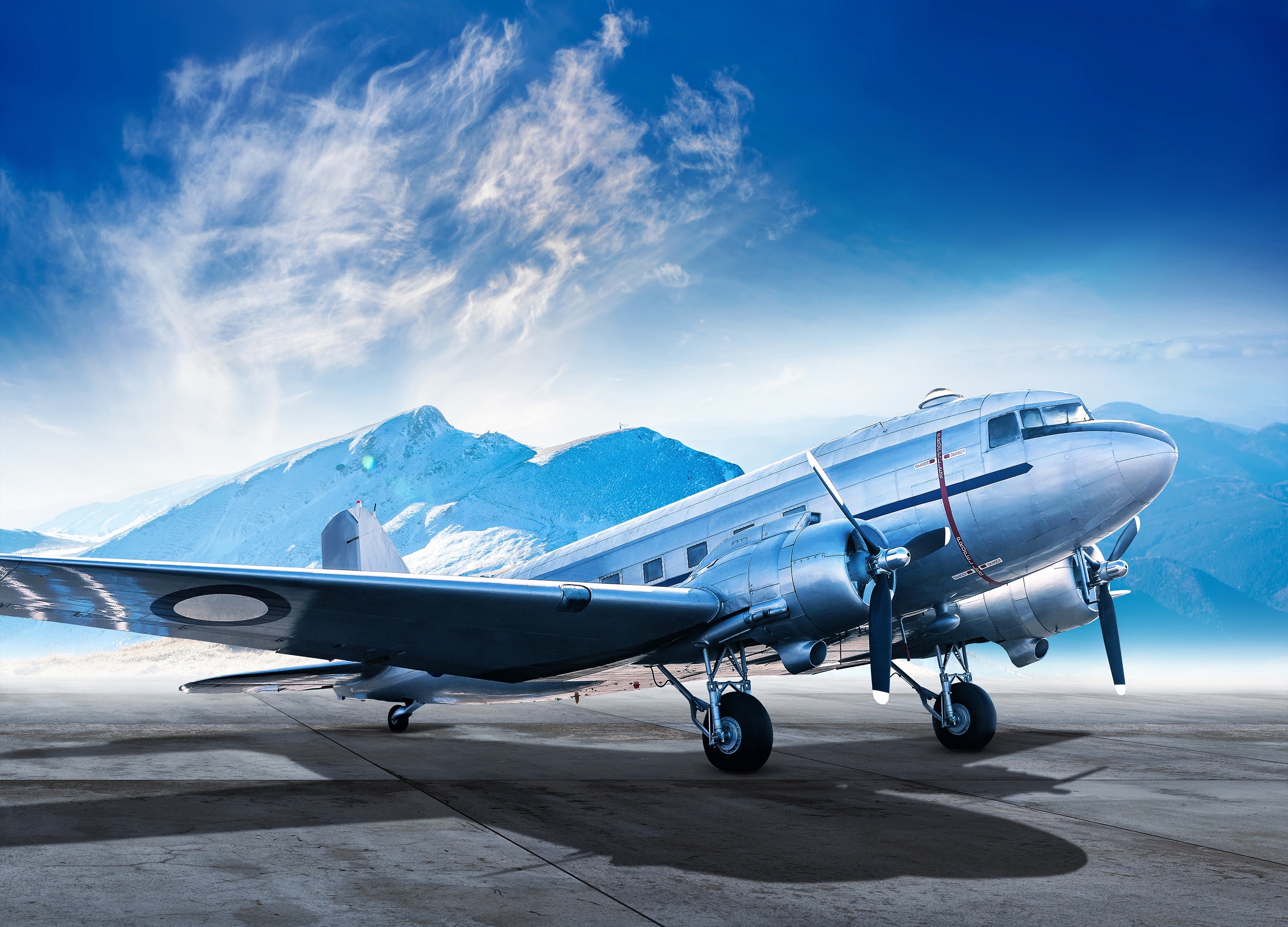 Vintage airplane on tarmac with snowy mountains HD Wallpaper