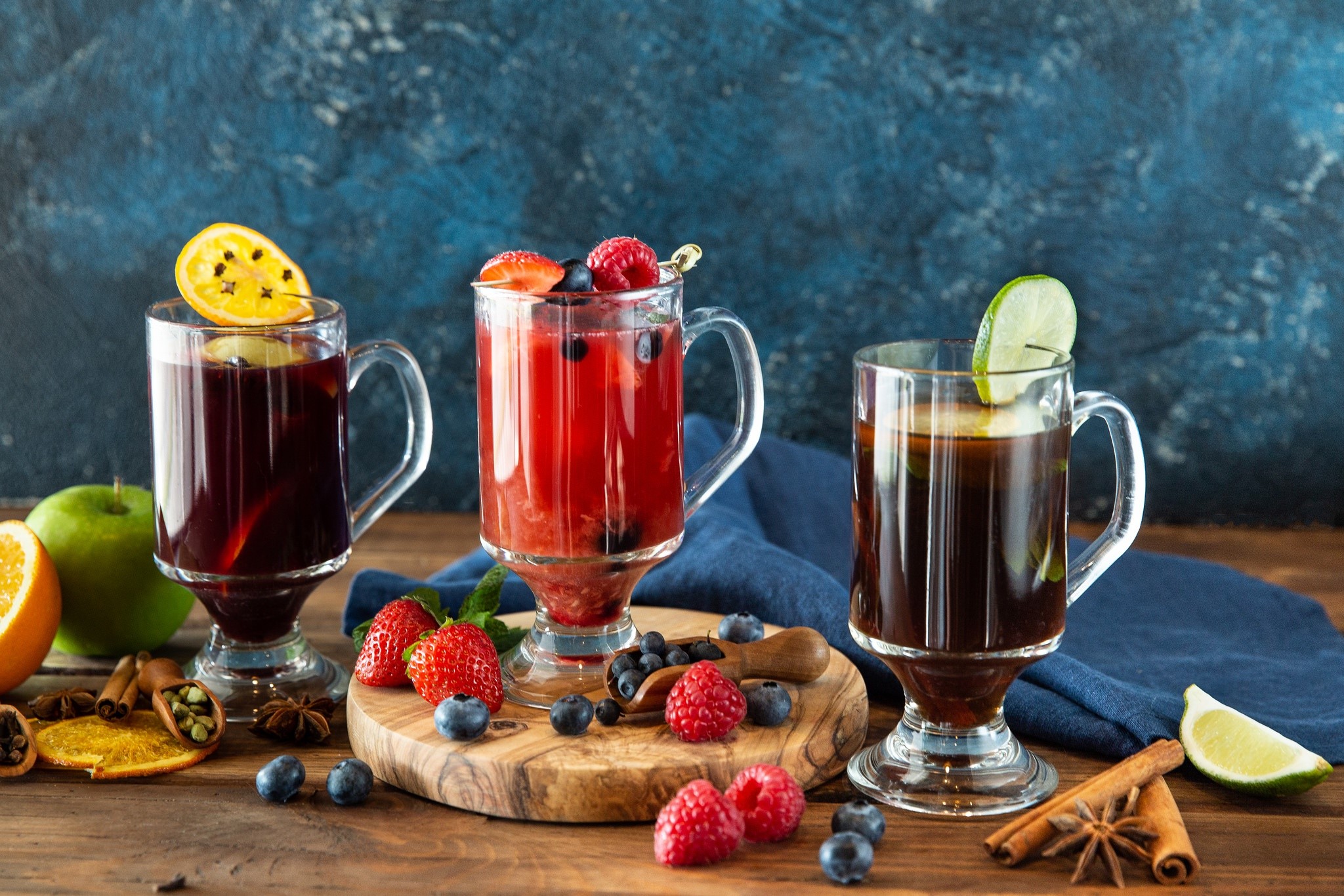 Three glasses of mulled wine and fruit on a wooden table HD Wallpaper