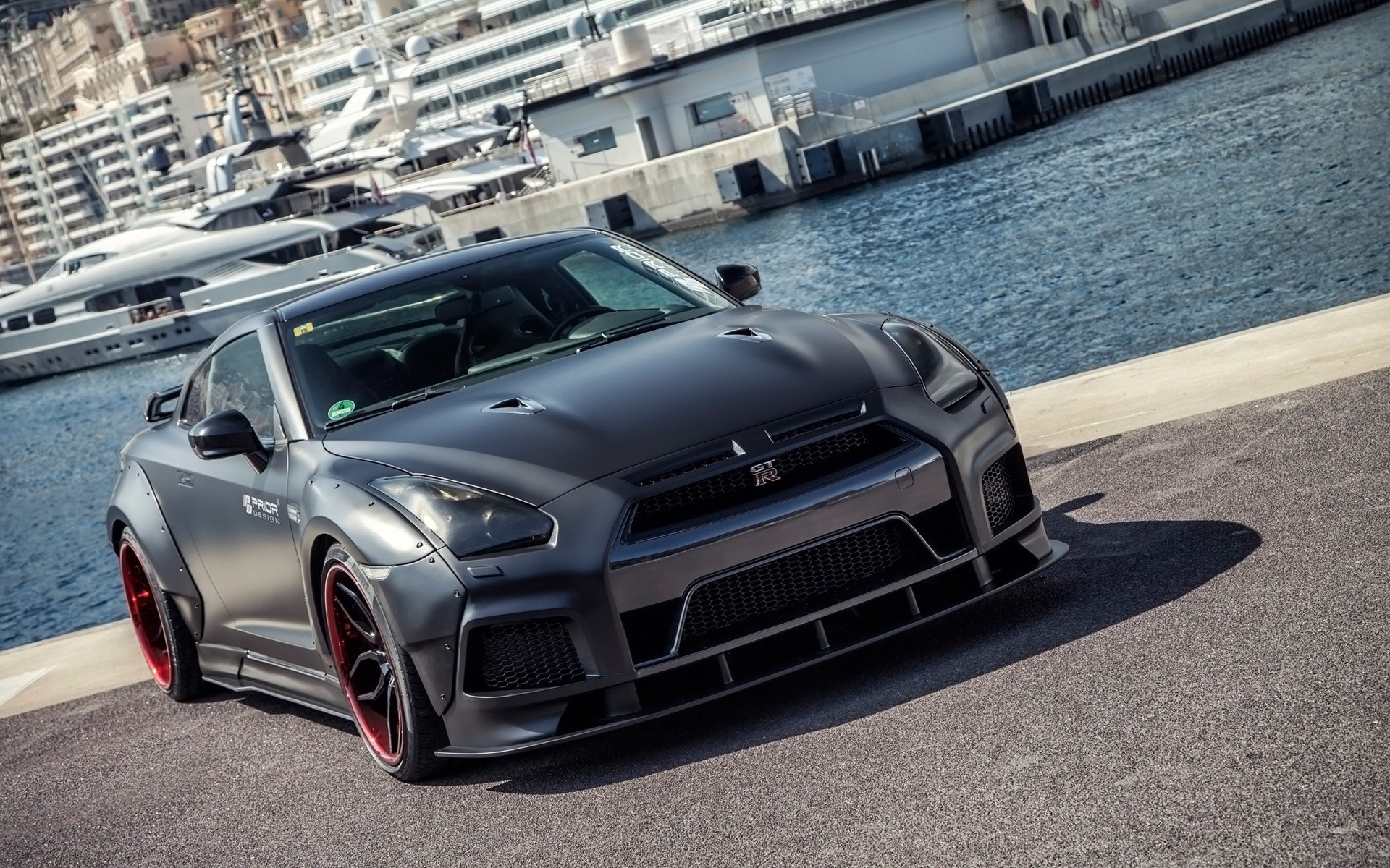 Matte black Nissan GT-R with red accents by the water HD Wallpaper