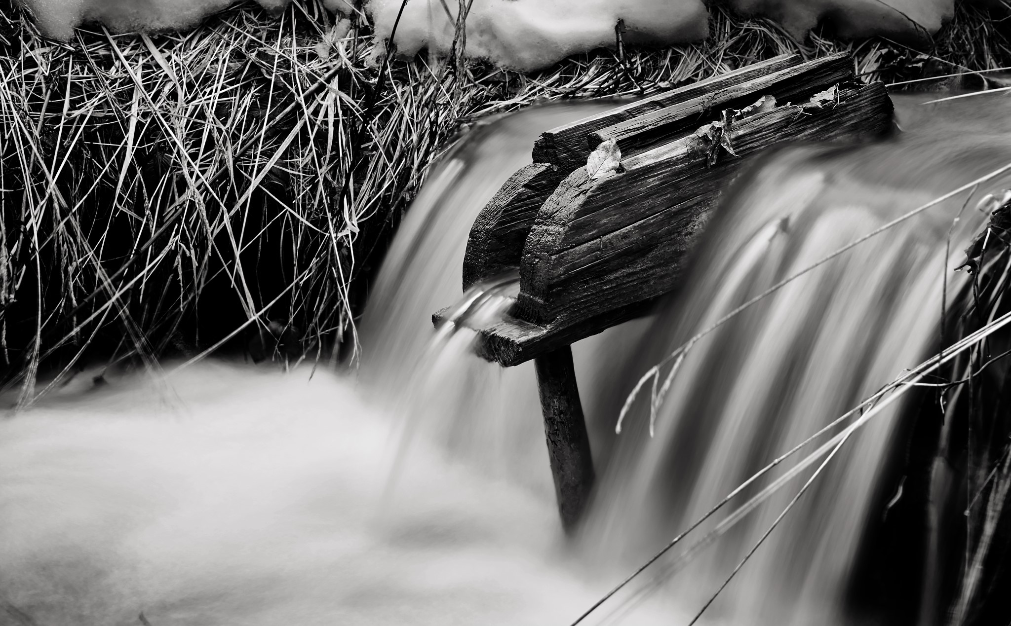 Monochrome long exposure of water flowing over wood HD Wallpaper