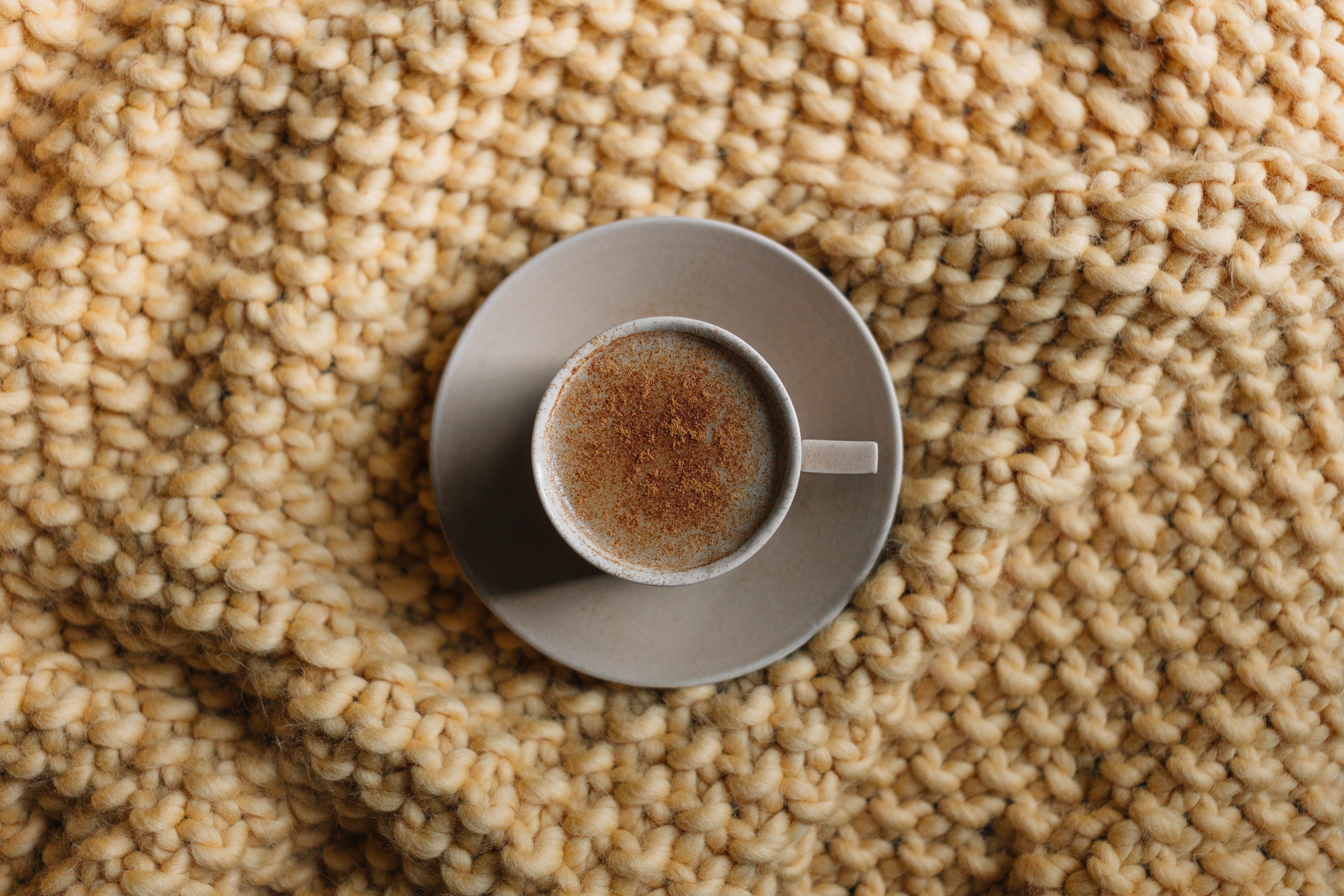 Cup of coffee with cinnamon on a knitted blanket HD Wallpaper