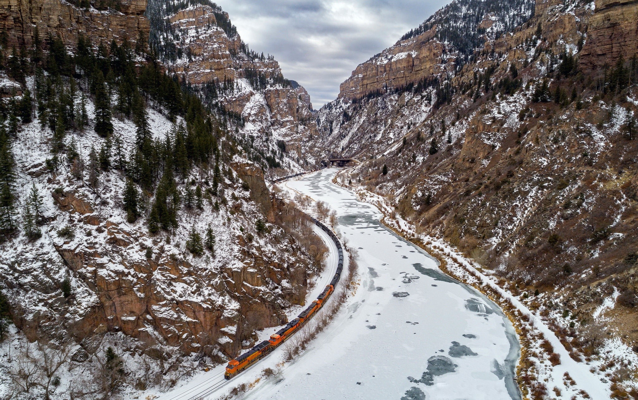 Train traveling through a snowy mountain gorge HD Wallpaper
