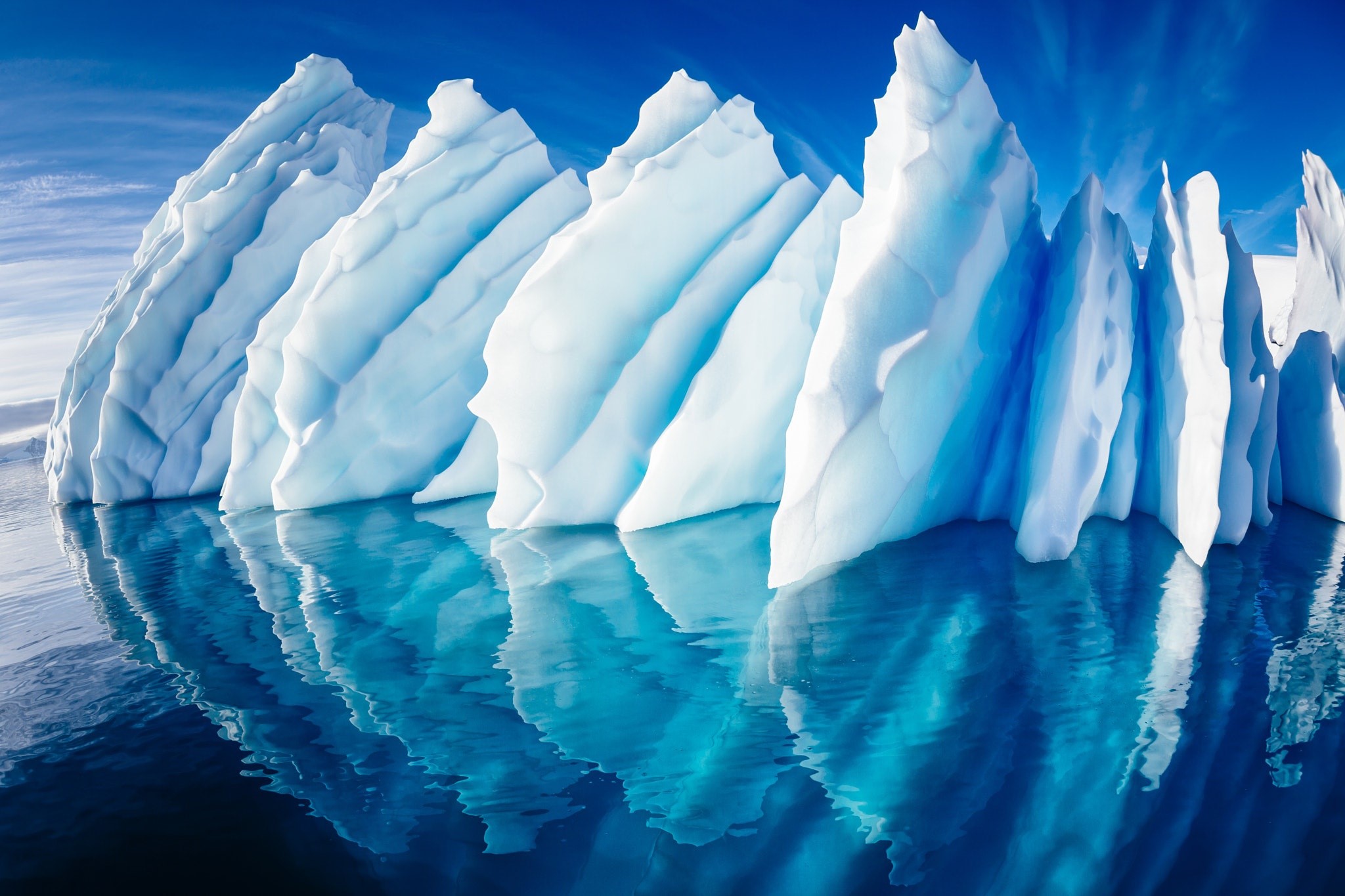 Icebergs reflecting in the ocean under a blue sky HD Wallpaper