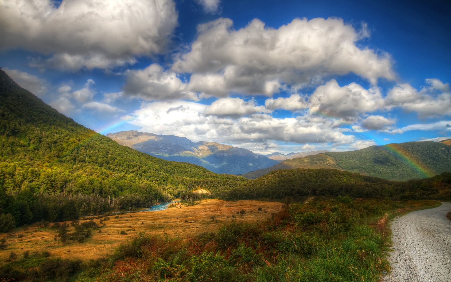 Mountain valley with a rainbow and a dirt road HD Wallpaper