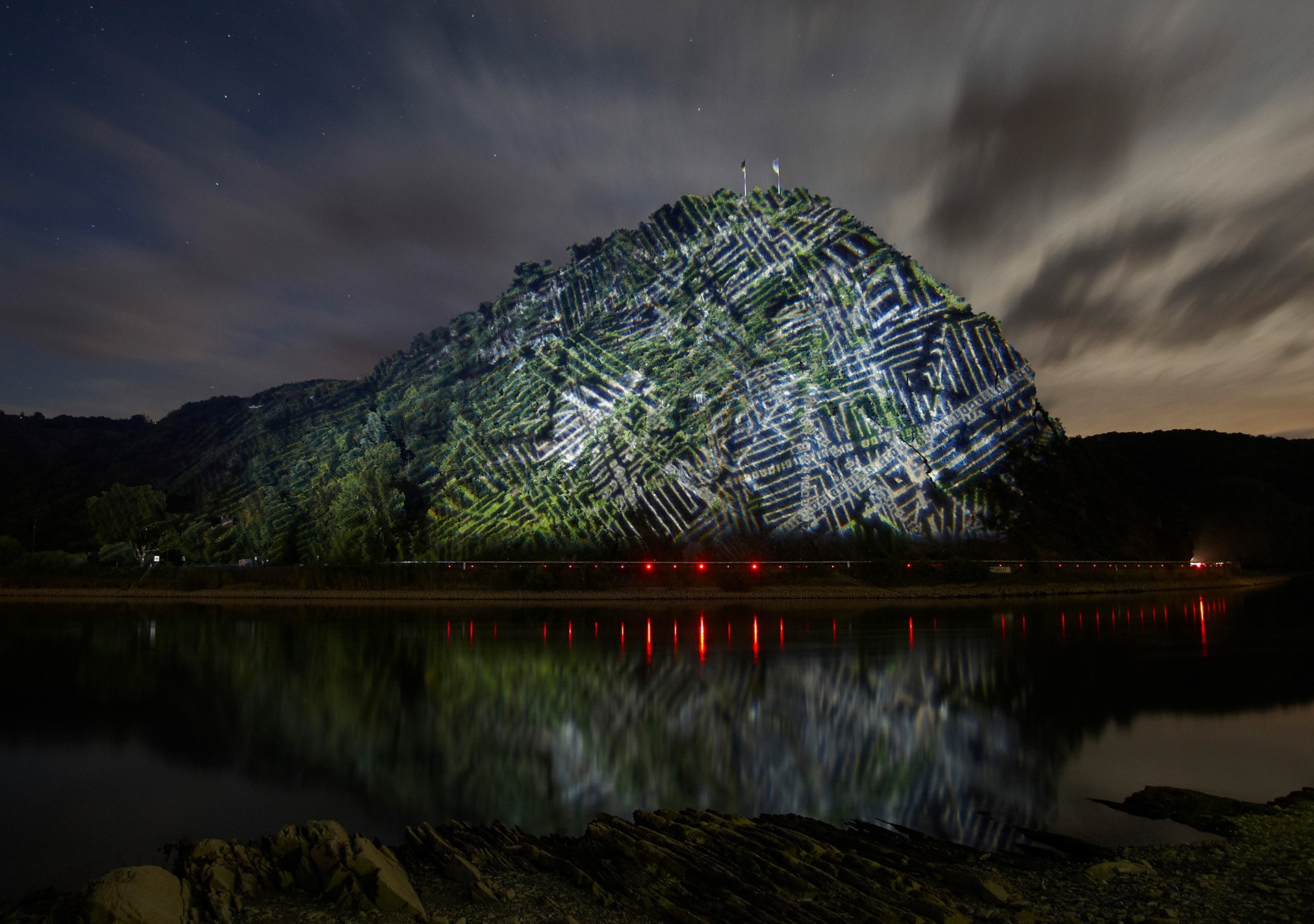 Mountain illuminated with light patterns at night with reflection HD Wallpaper