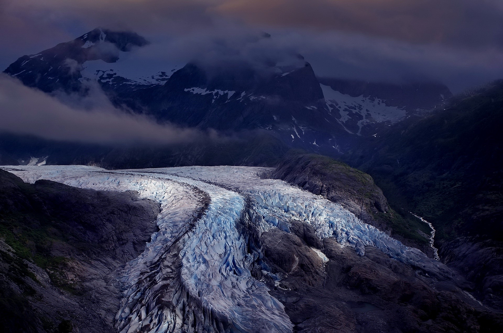 Glacier winding through mountains under clouds HD Wallpaper