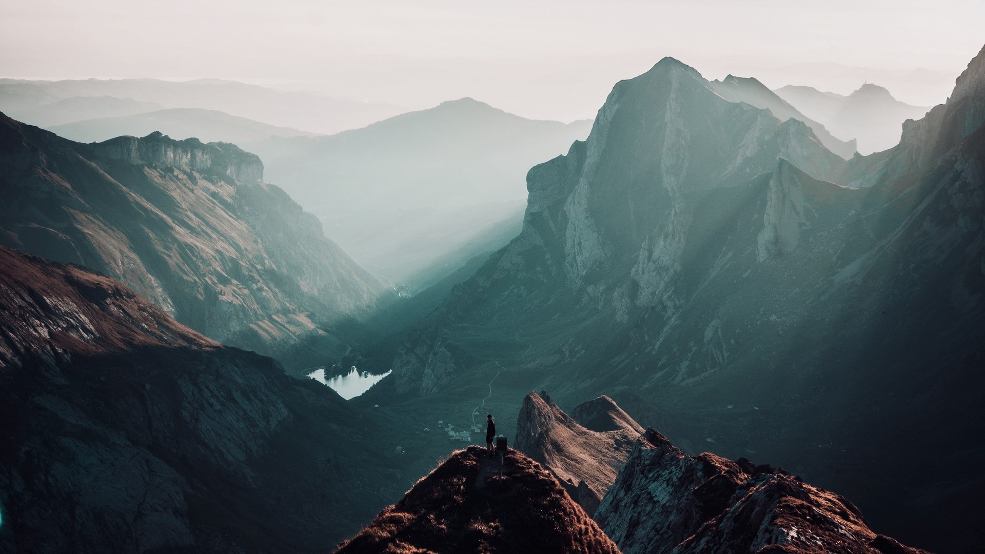 Person standing on a mountain peak in Switzerland HD Wallpaper