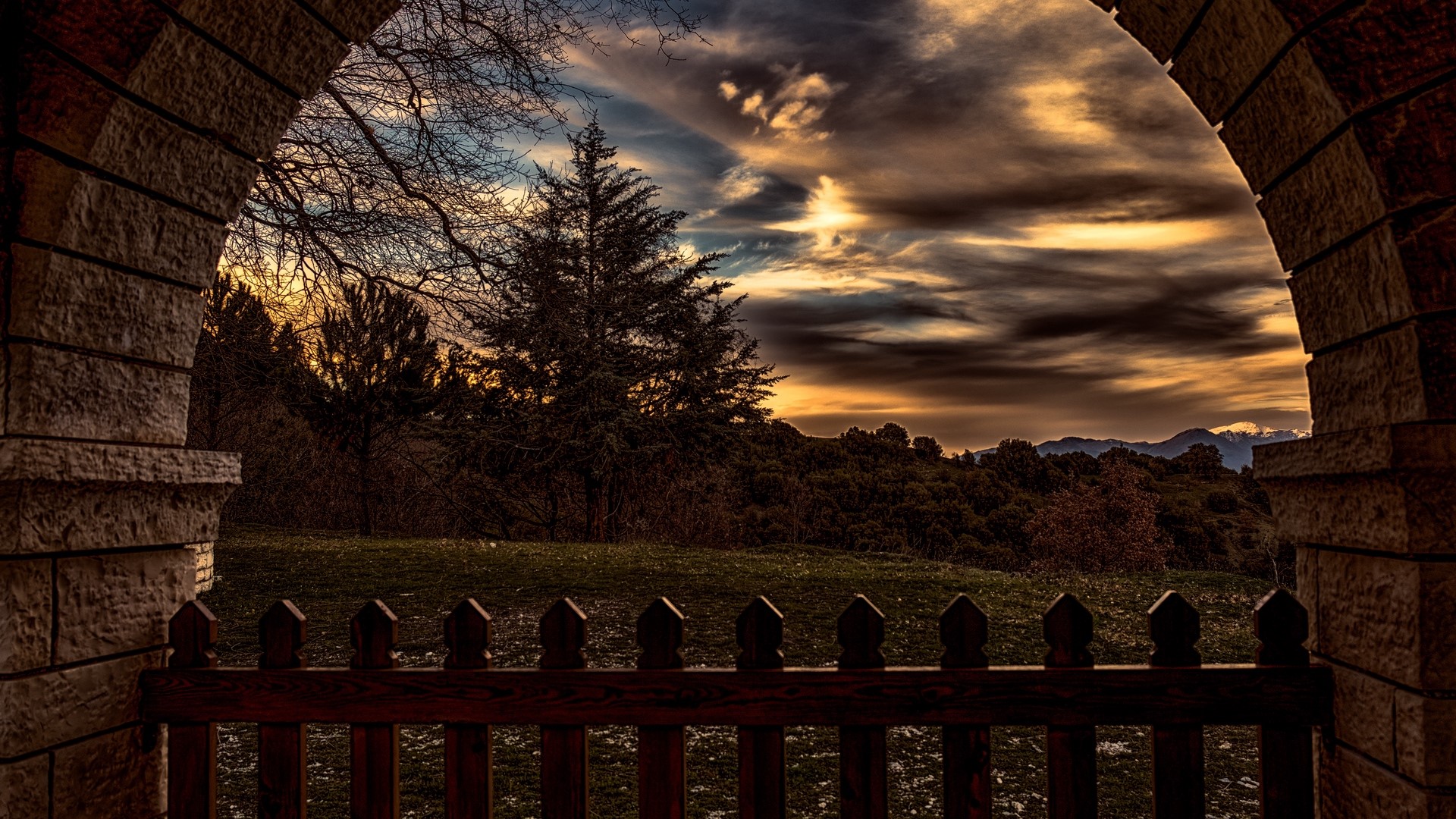 Archway overlooking sunset over hills and trees HD Wallpaper