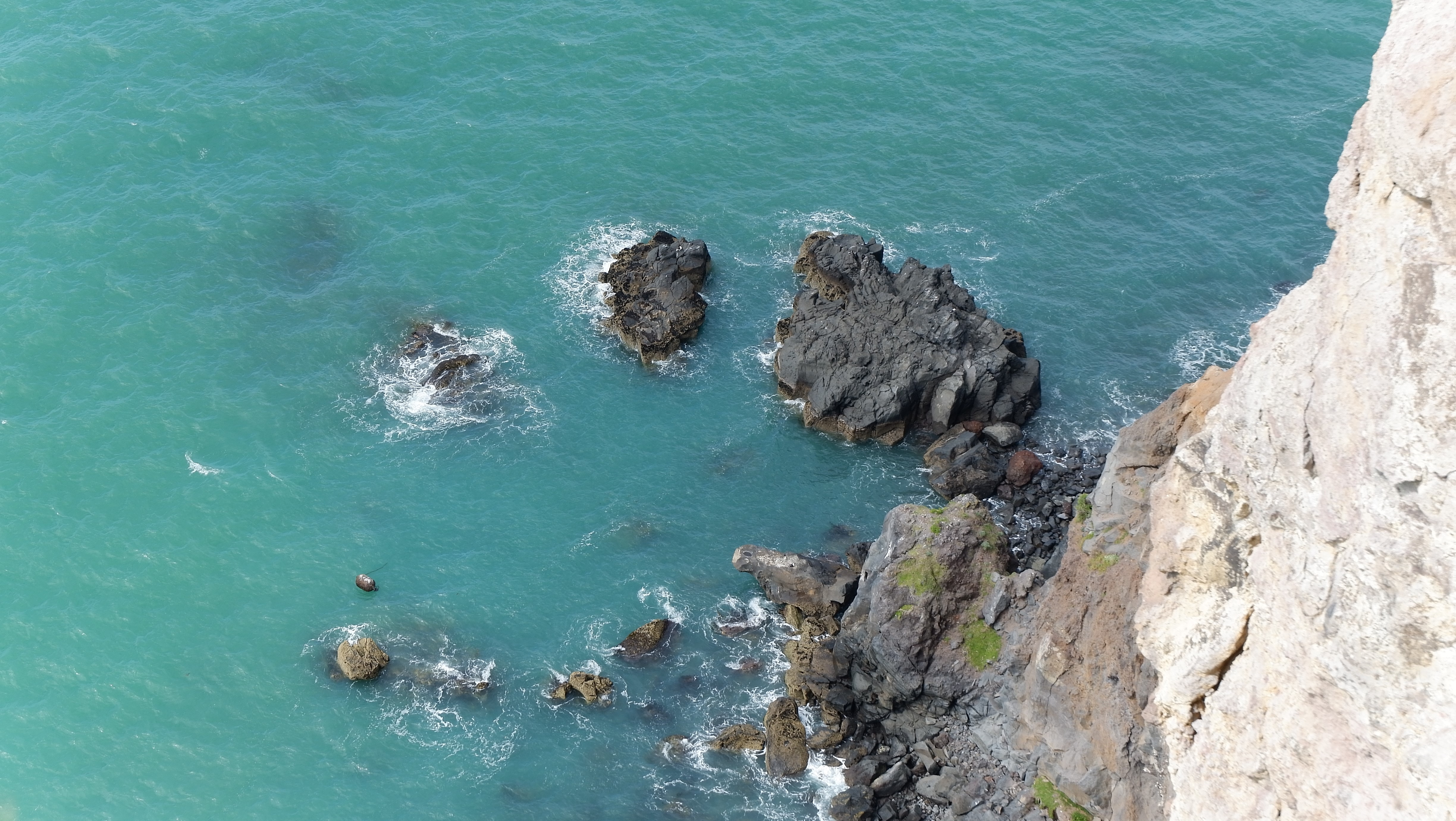4K rocks in turquoise water near cliff HD Wallpaper