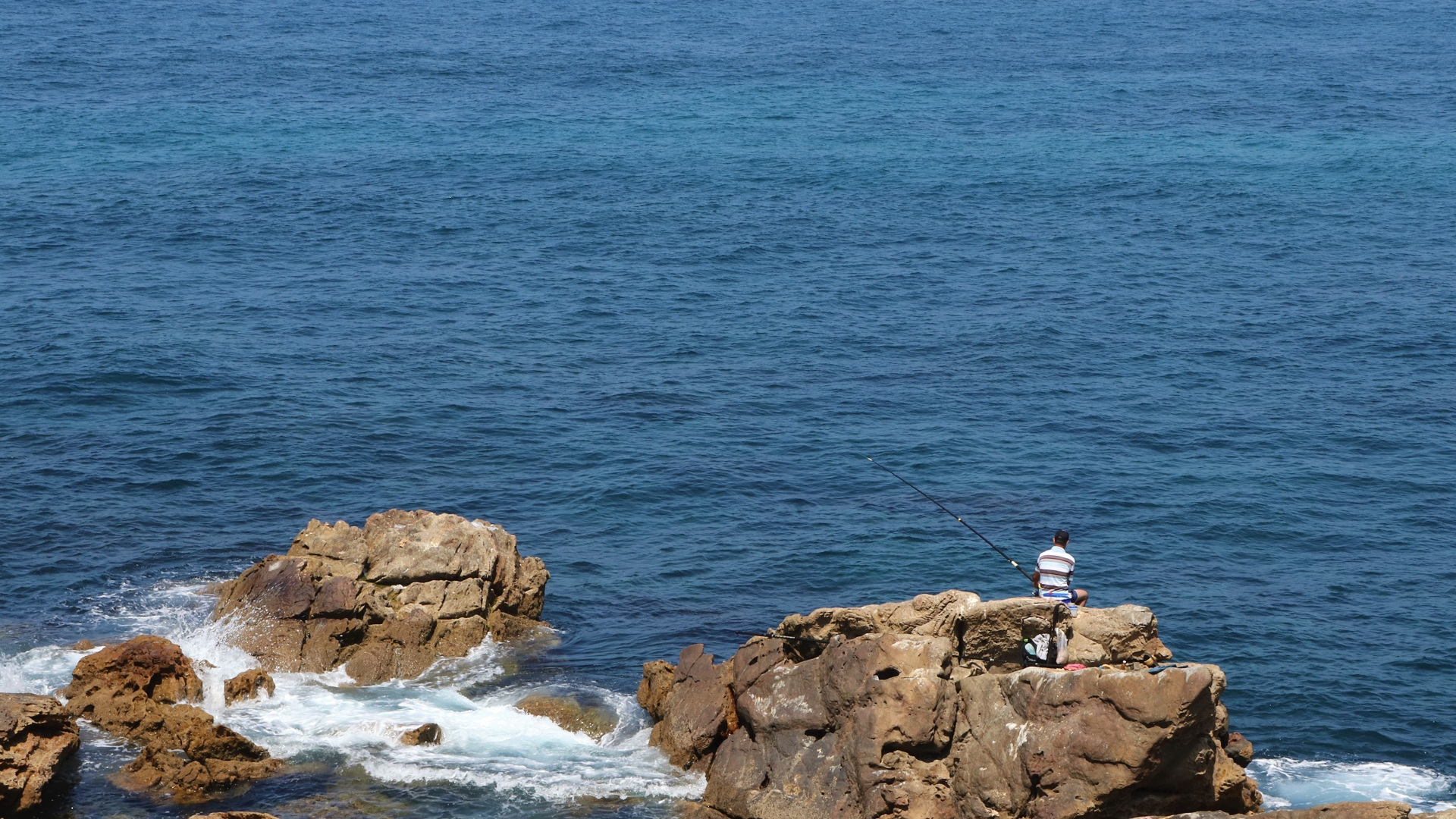 Man fishing on rocks in the Atlantic Ocean HD Wallpaper