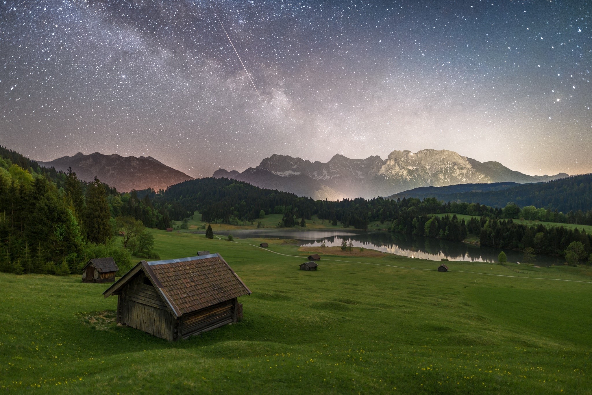 Wooden cabins in a grassy field under the Milky Way HD Wallpaper