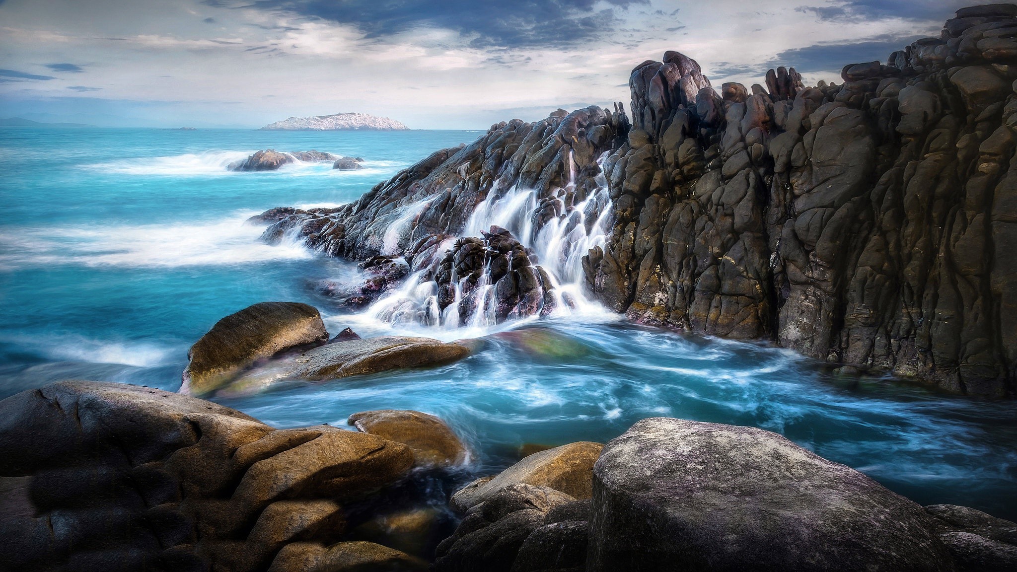 Long exposure of waves crashing on rocky cliffs by the sea HD Wallpaper