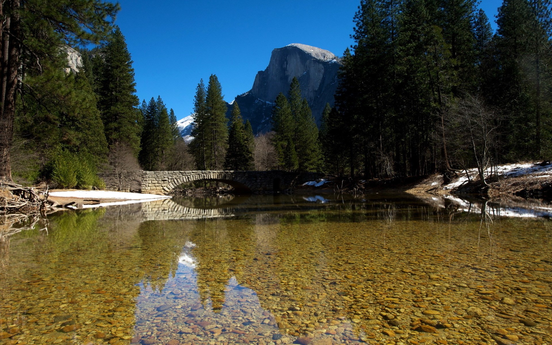 Stone bridge over a river with Half Dome in the background HD Wallpaper