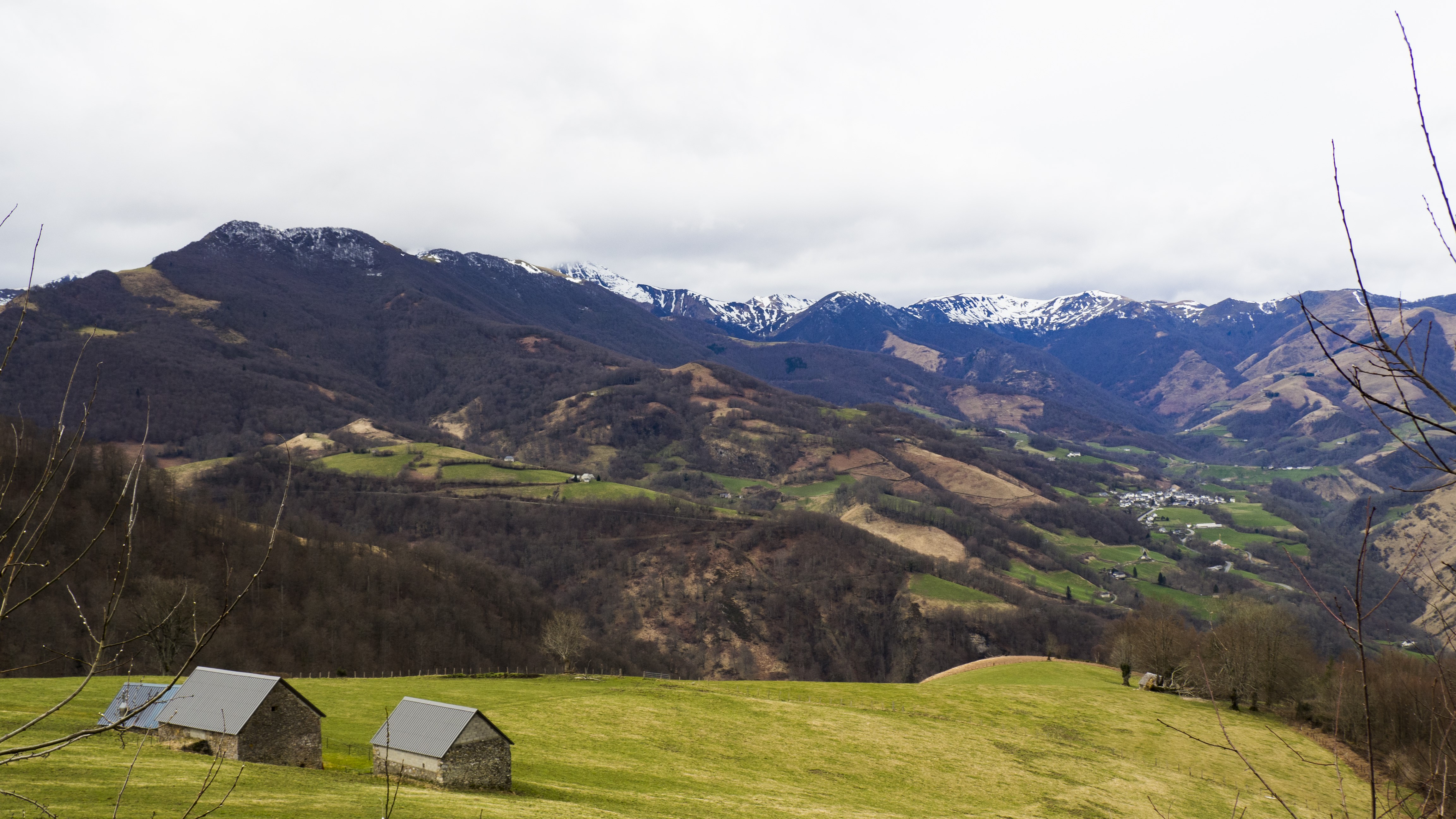 Mountain landscape with snow-capped peaks and small stone buildings HD Wallpaper