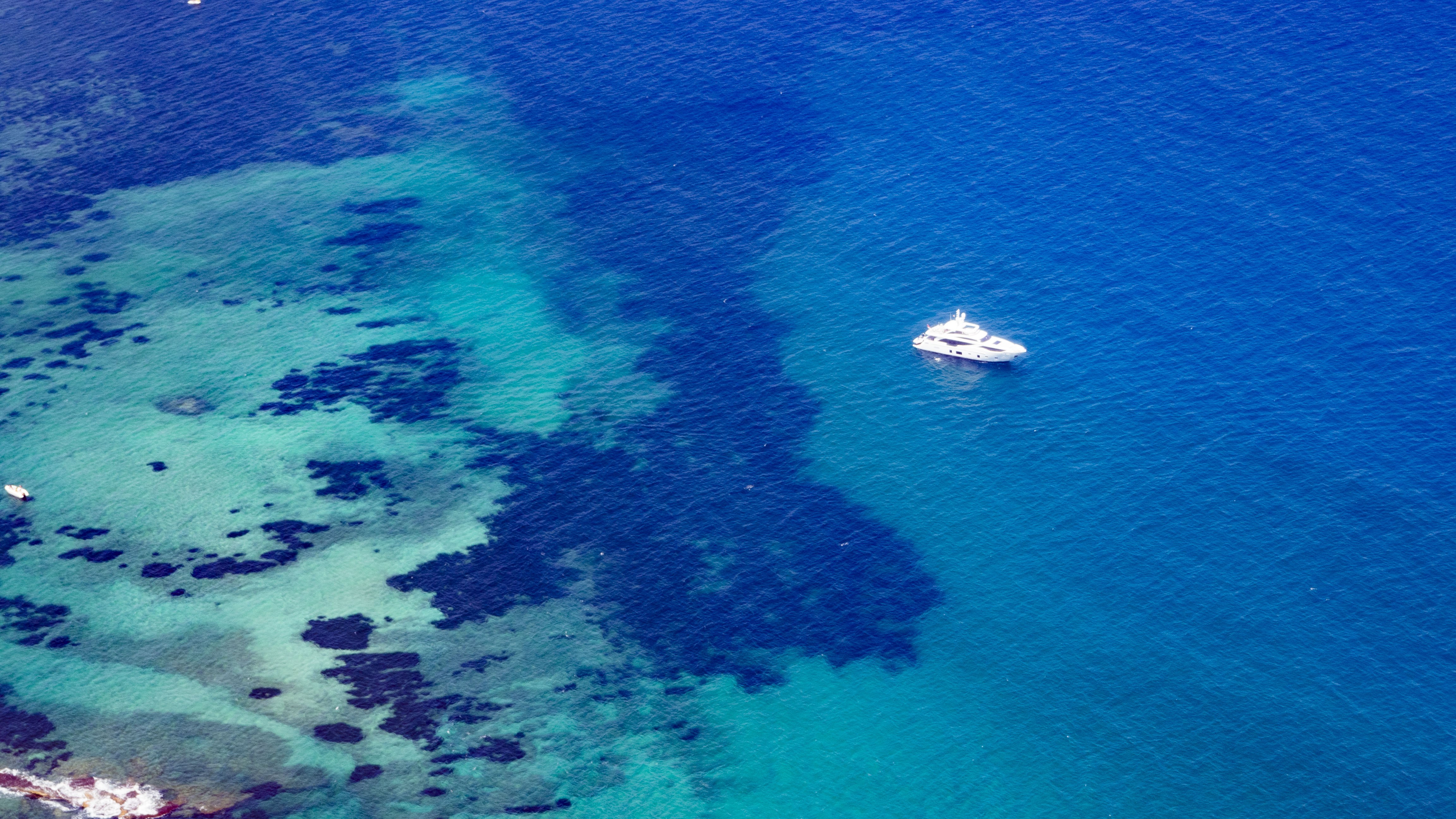 Aerial view of a yacht in the sea near a coast HD Wallpaper
