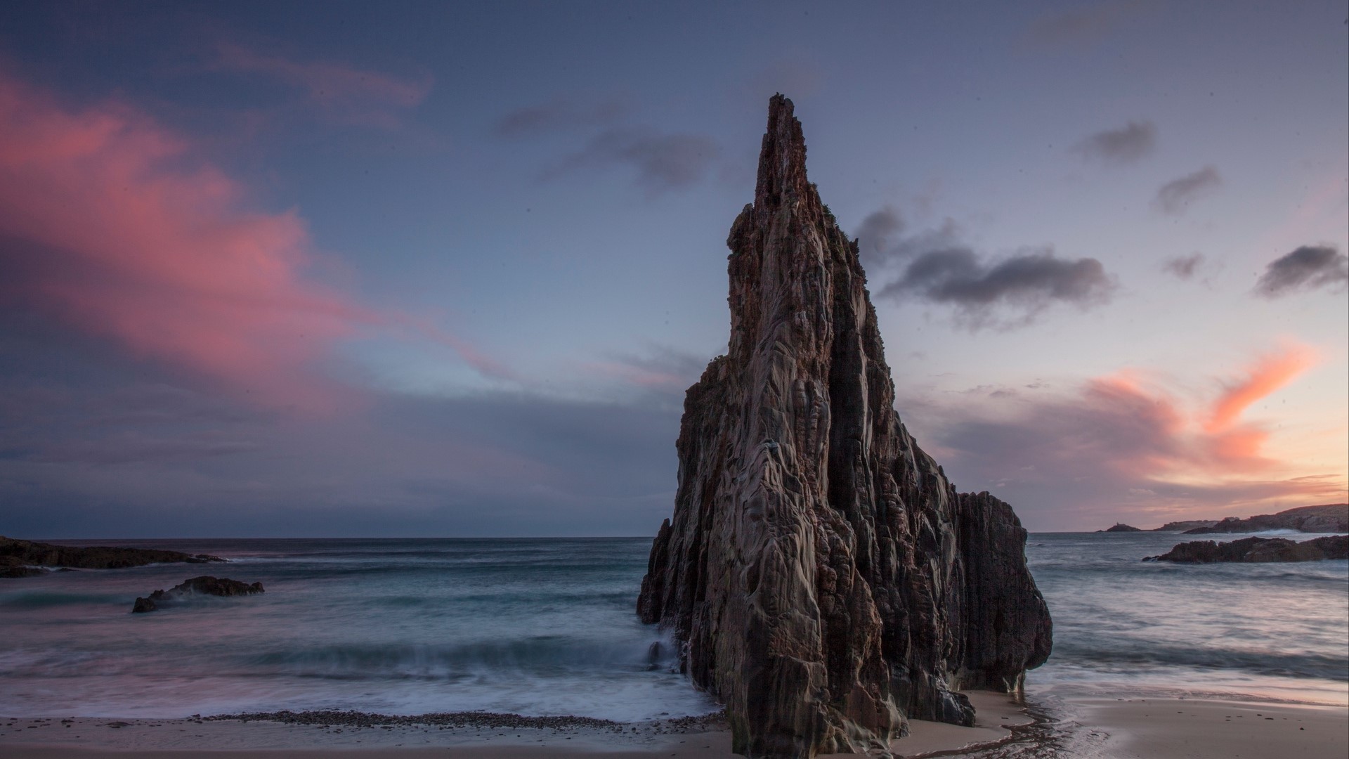 Jagged rock formation on a beach at sunset HD Wallpaper