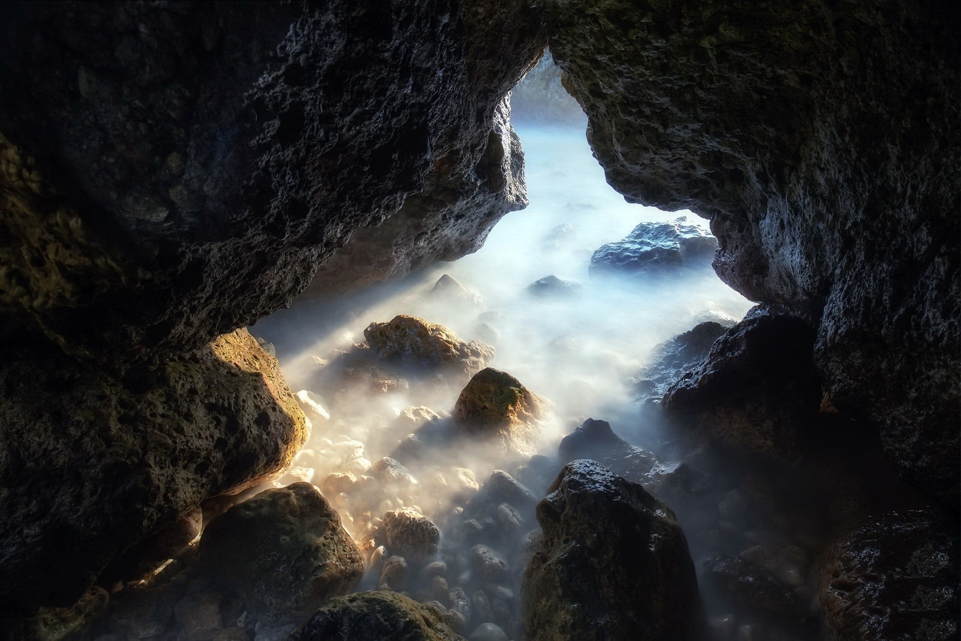 Sunlight streaming into a rocky sea cave HD Wallpaper