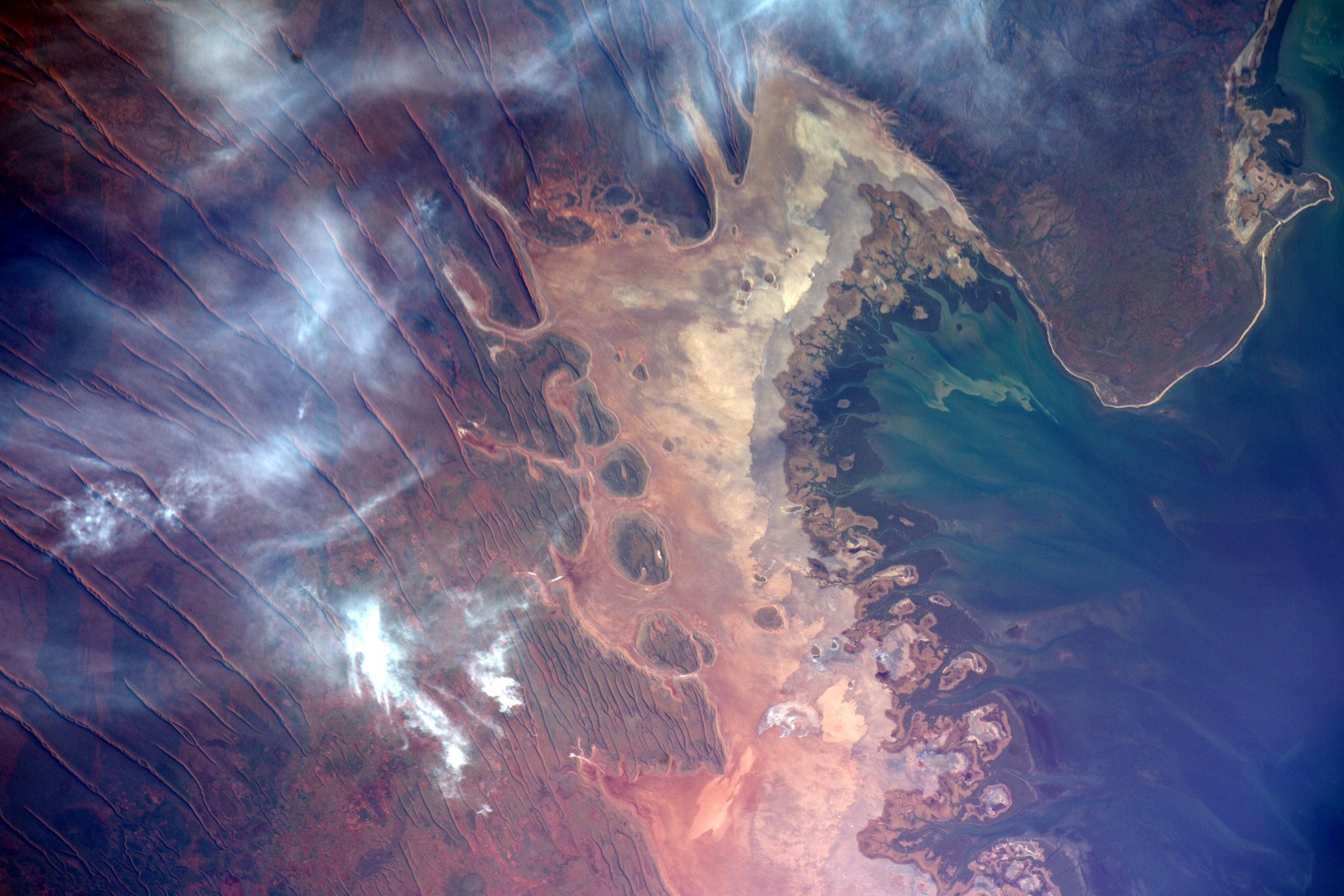 Aerial view of a coastal landscape with smoke plumes HD Wallpaper