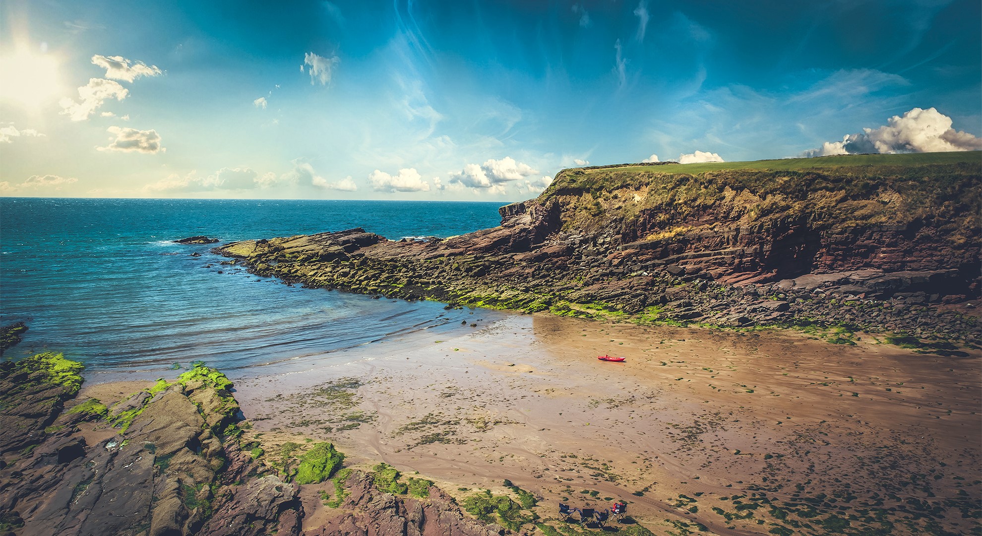 Red kayak on a sandy beach with rocky cliffs and the sea HD Wallpaper