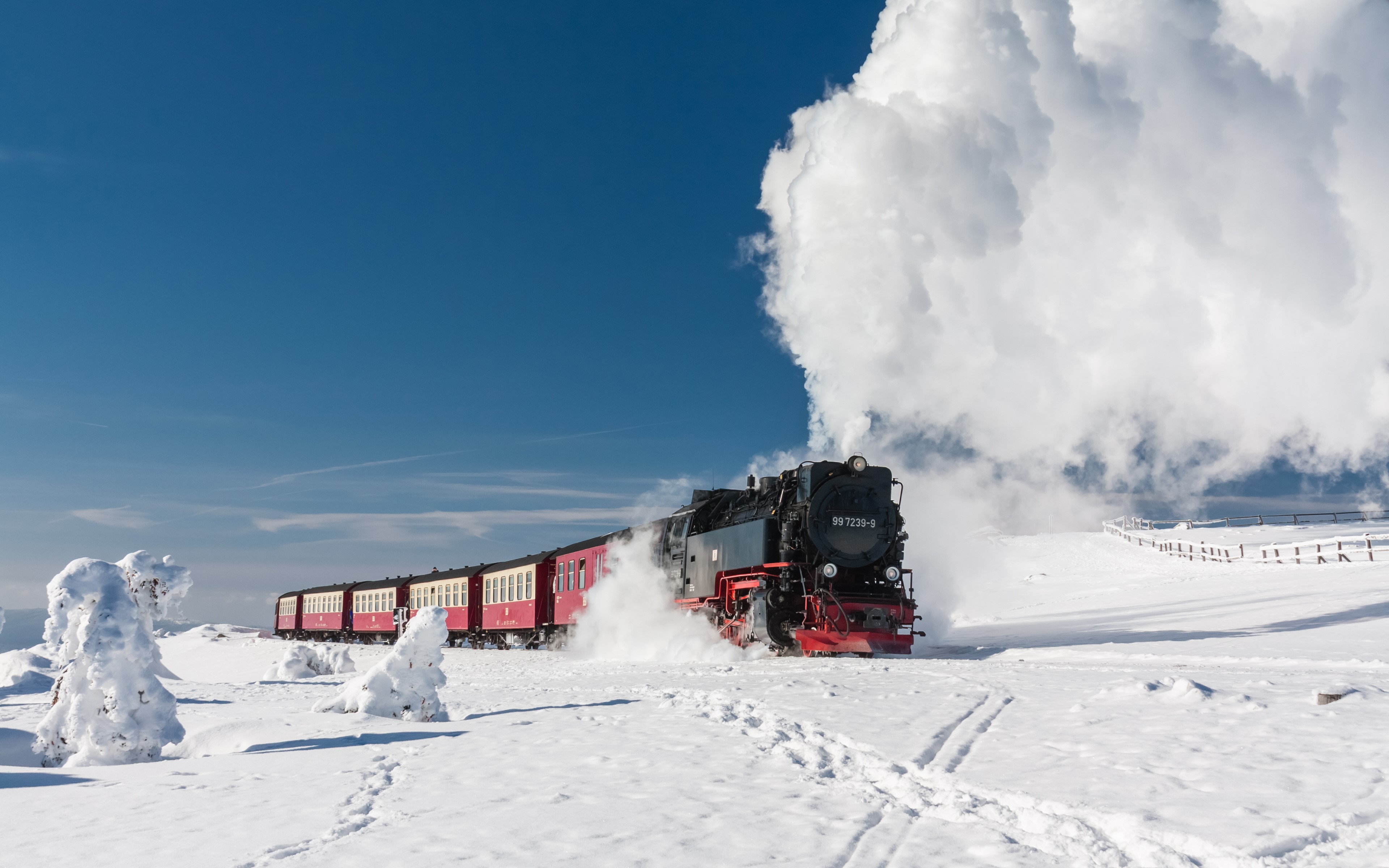 Steam locomotive pulling train through snowy landscape HD Wallpaper