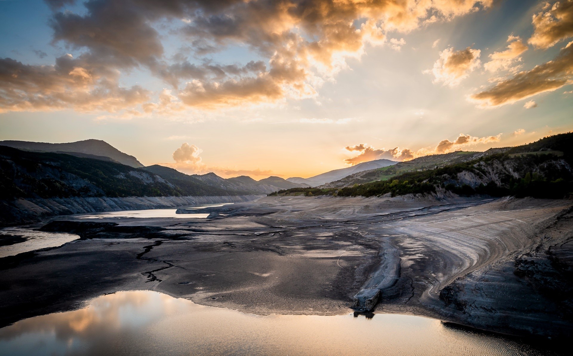Cracked earth and water at sunset with mountains HD Wallpaper