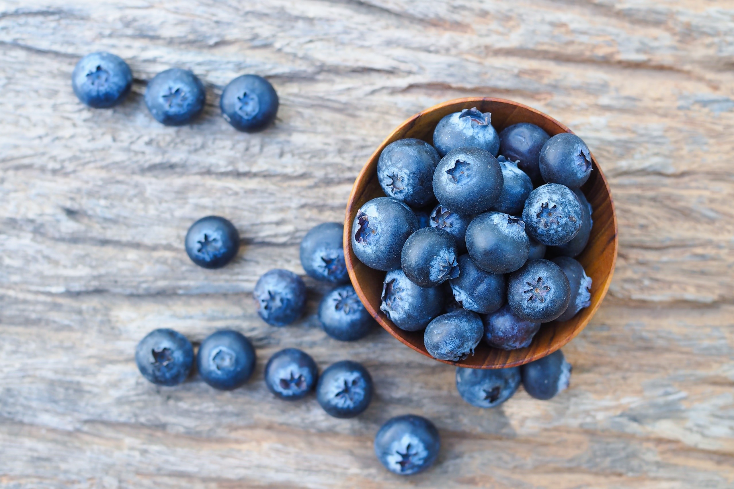 Blueberries in a wooden bowl on a wooden surface HD Wallpaper