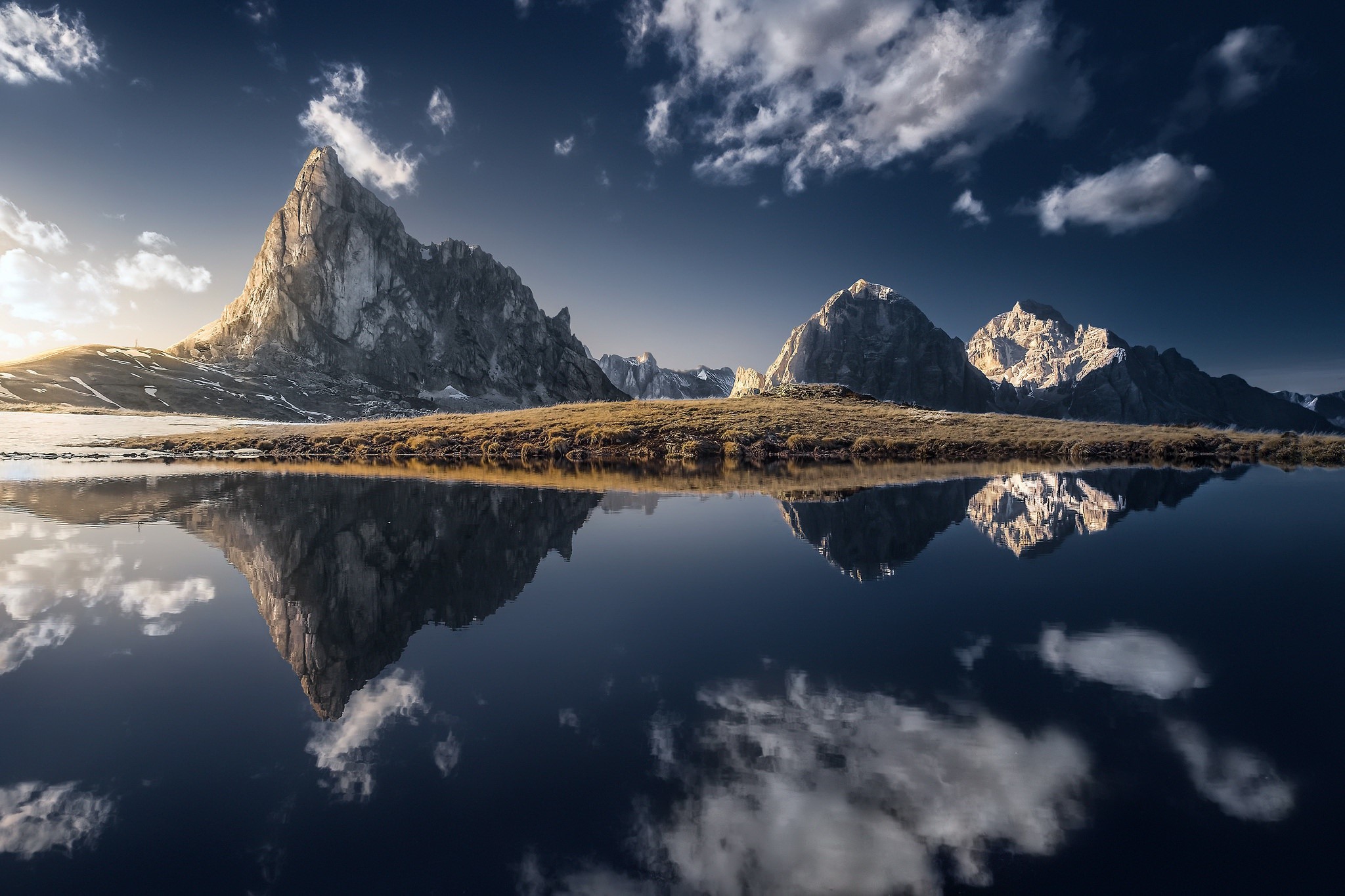Mountain range reflected in a calm lake under a cloudy sky HD Wallpaper