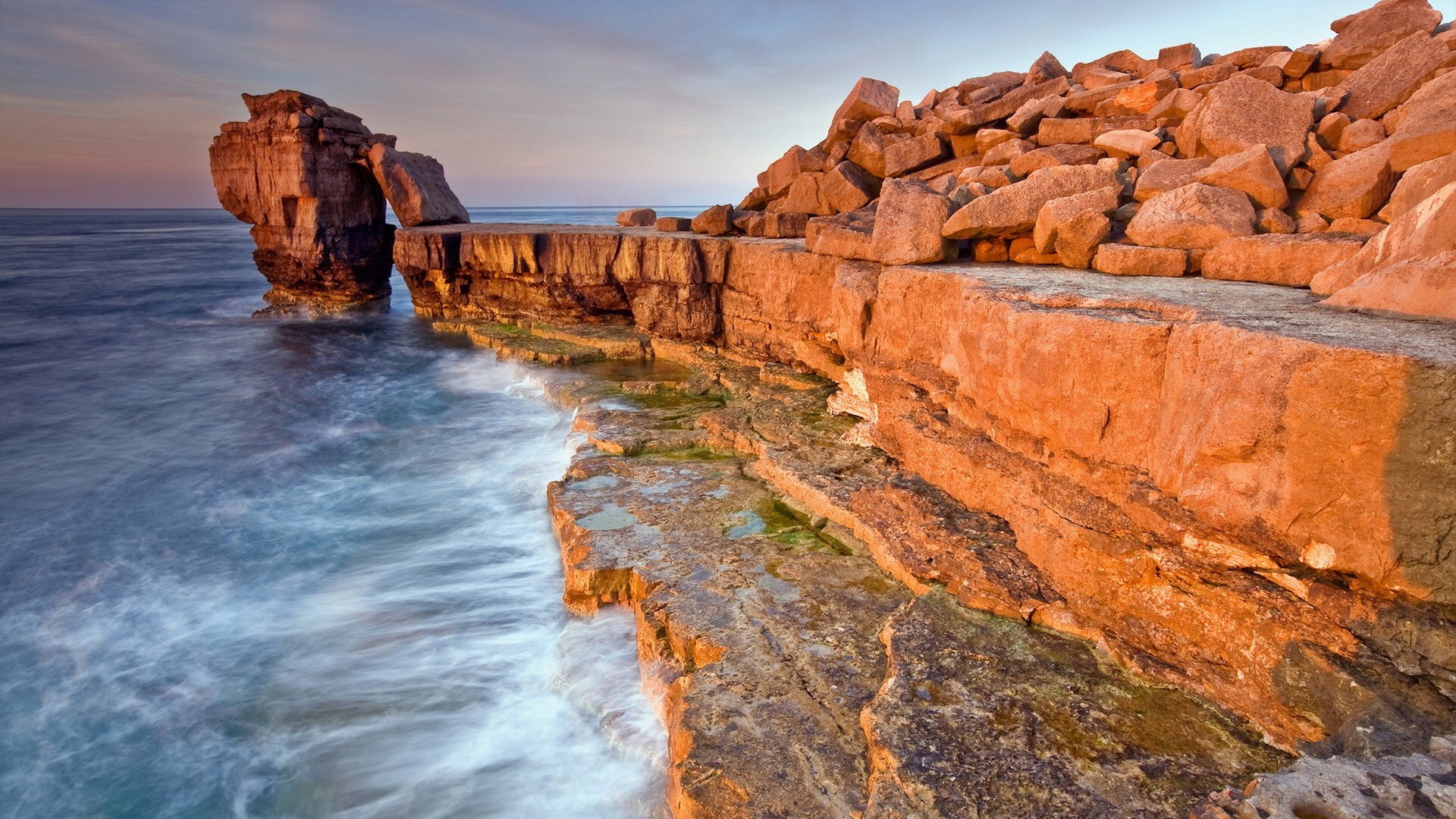 Rocky coastline with waves crashing against cliffs HD Wallpaper