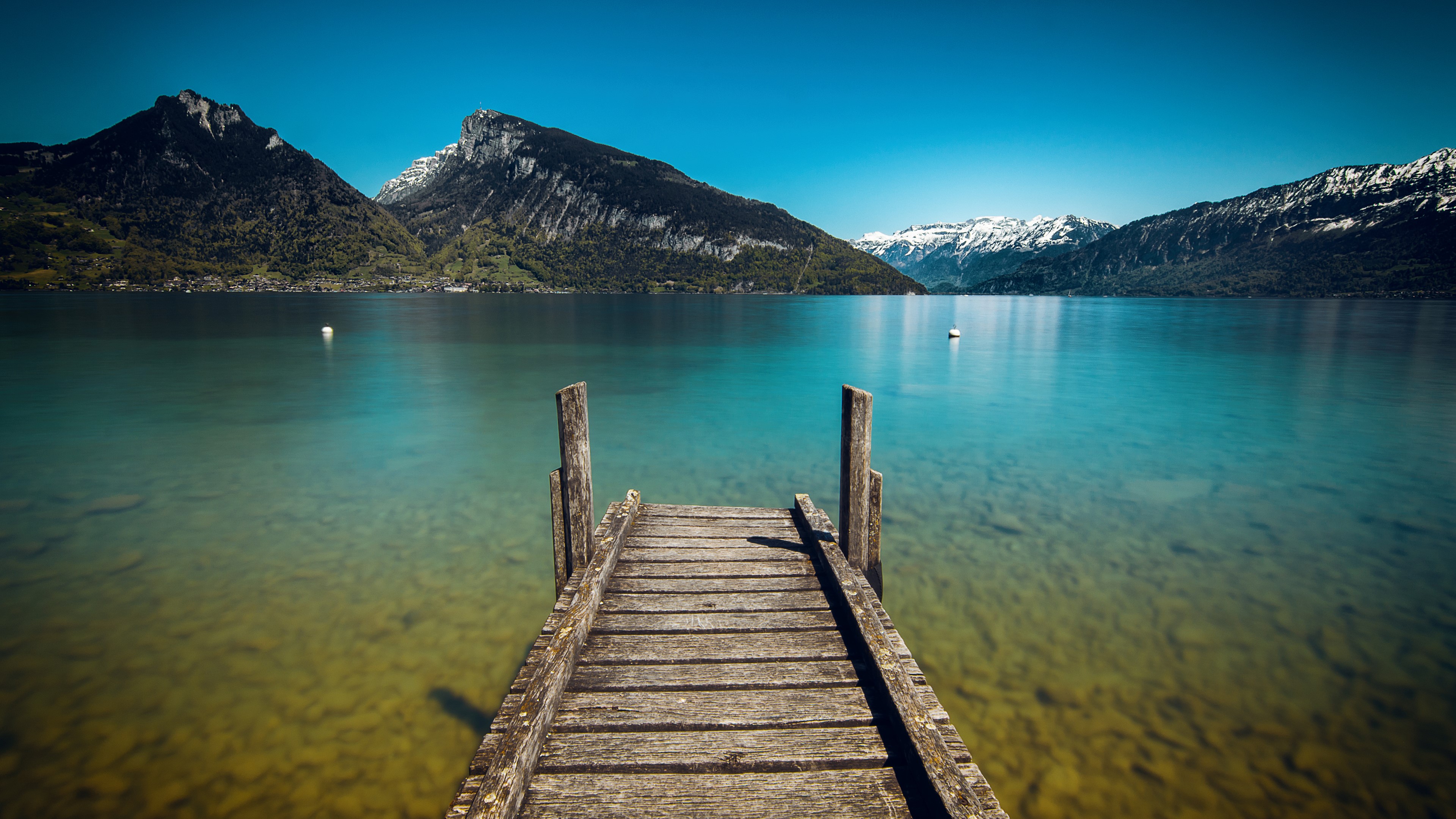 Wooden pier on a clear lake with mountains HD Wallpaper
