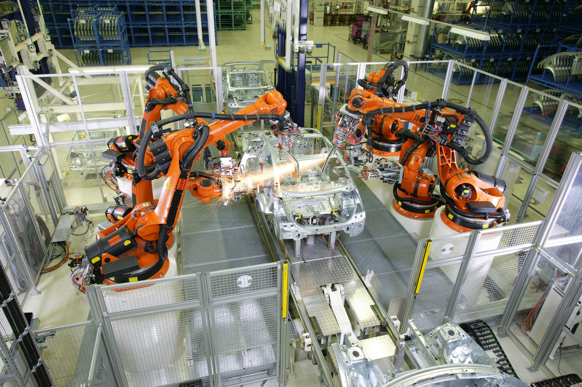 Robots welding car chassis on an assembly line HD Wallpaper