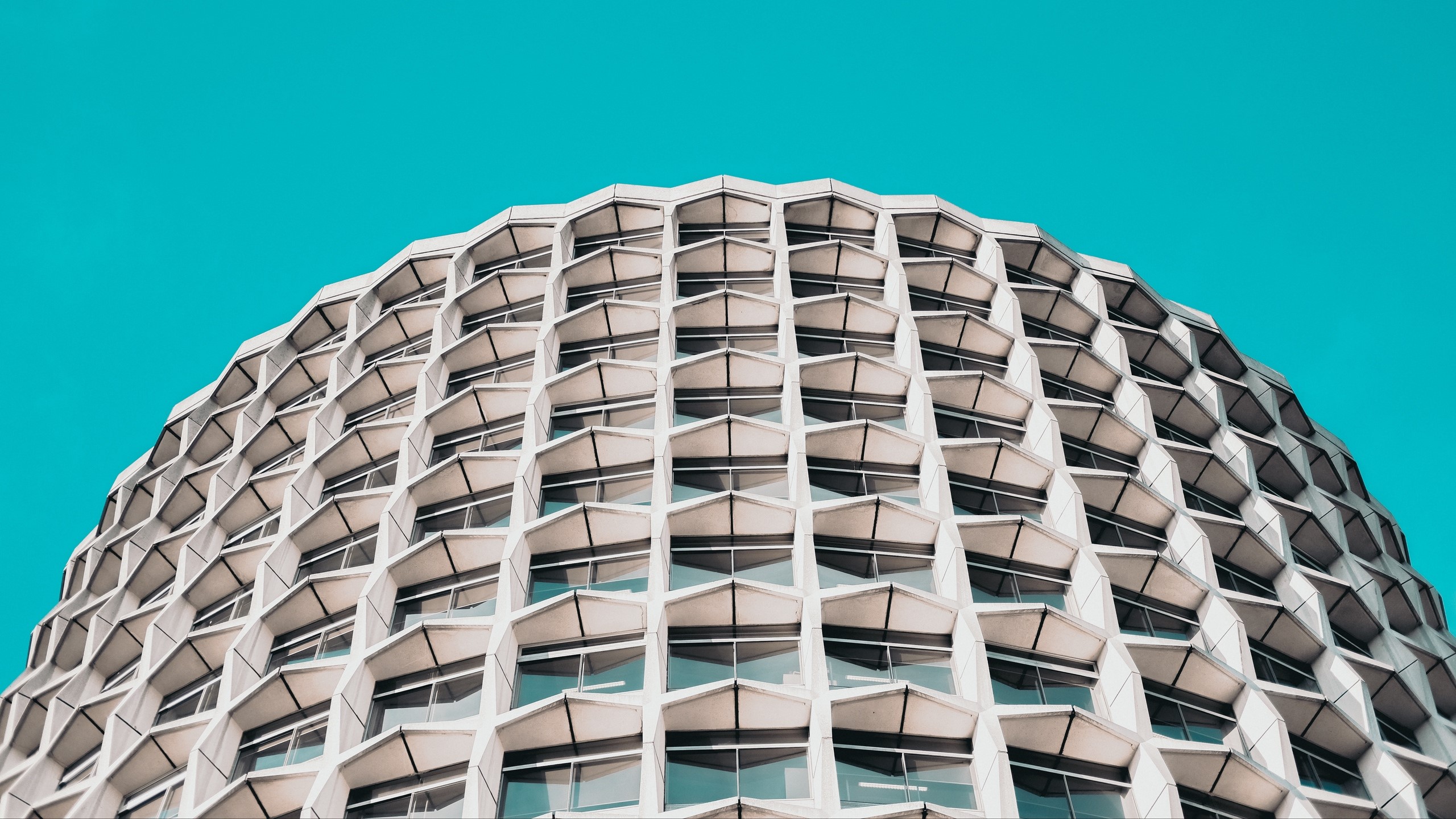 Modern honeycomb building against a cyan sky HD Wallpaper